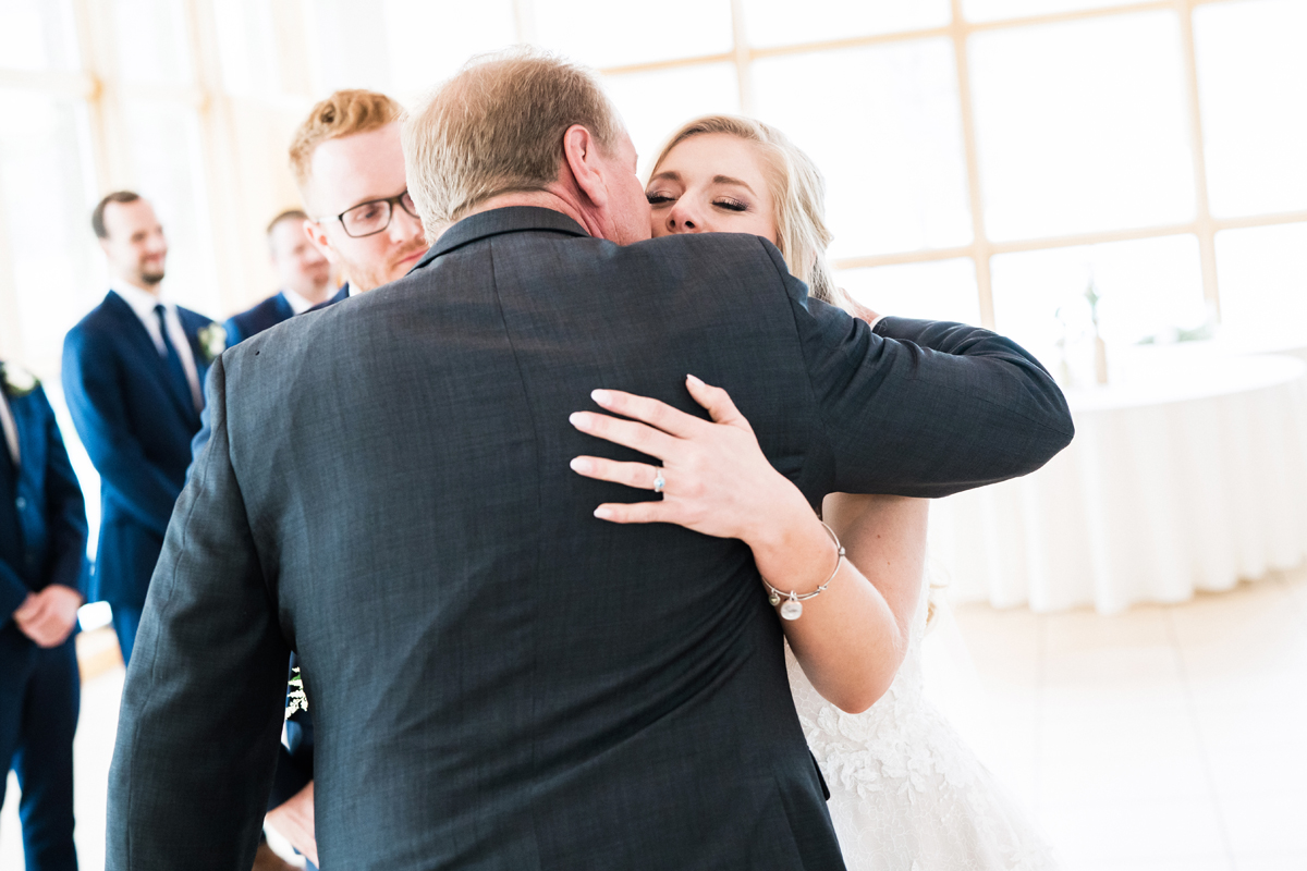 Dad embraces his daughter at wedding ceremony.