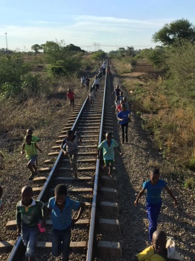 Local children celebrating by trying to keep up with the train!