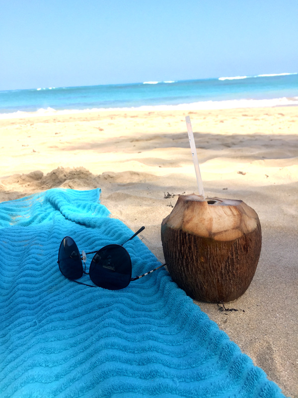 punta cana beach sunglasses towel and coconut drink