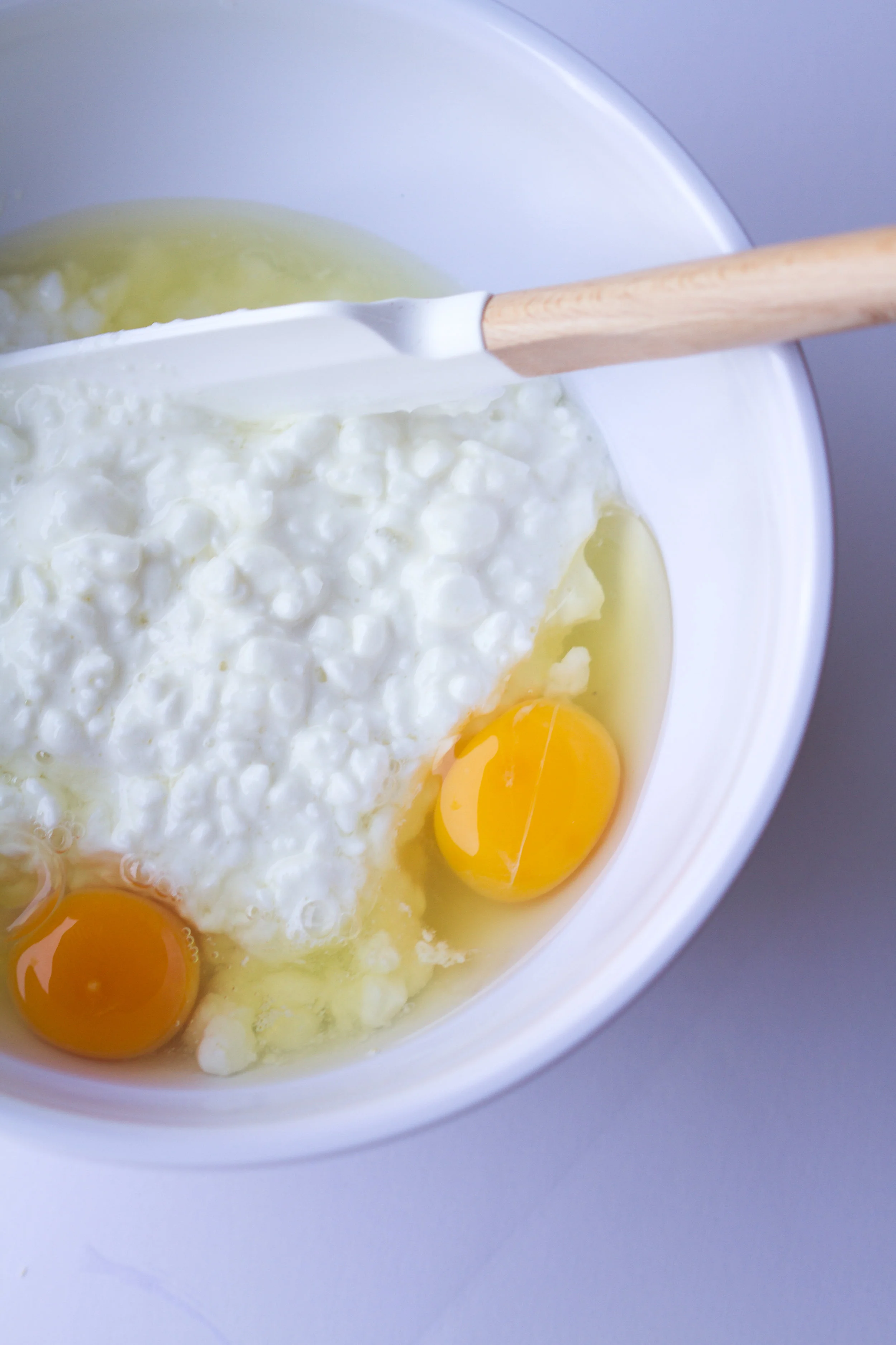 cottage cheese and eggs in a bowl with a wooden spoon