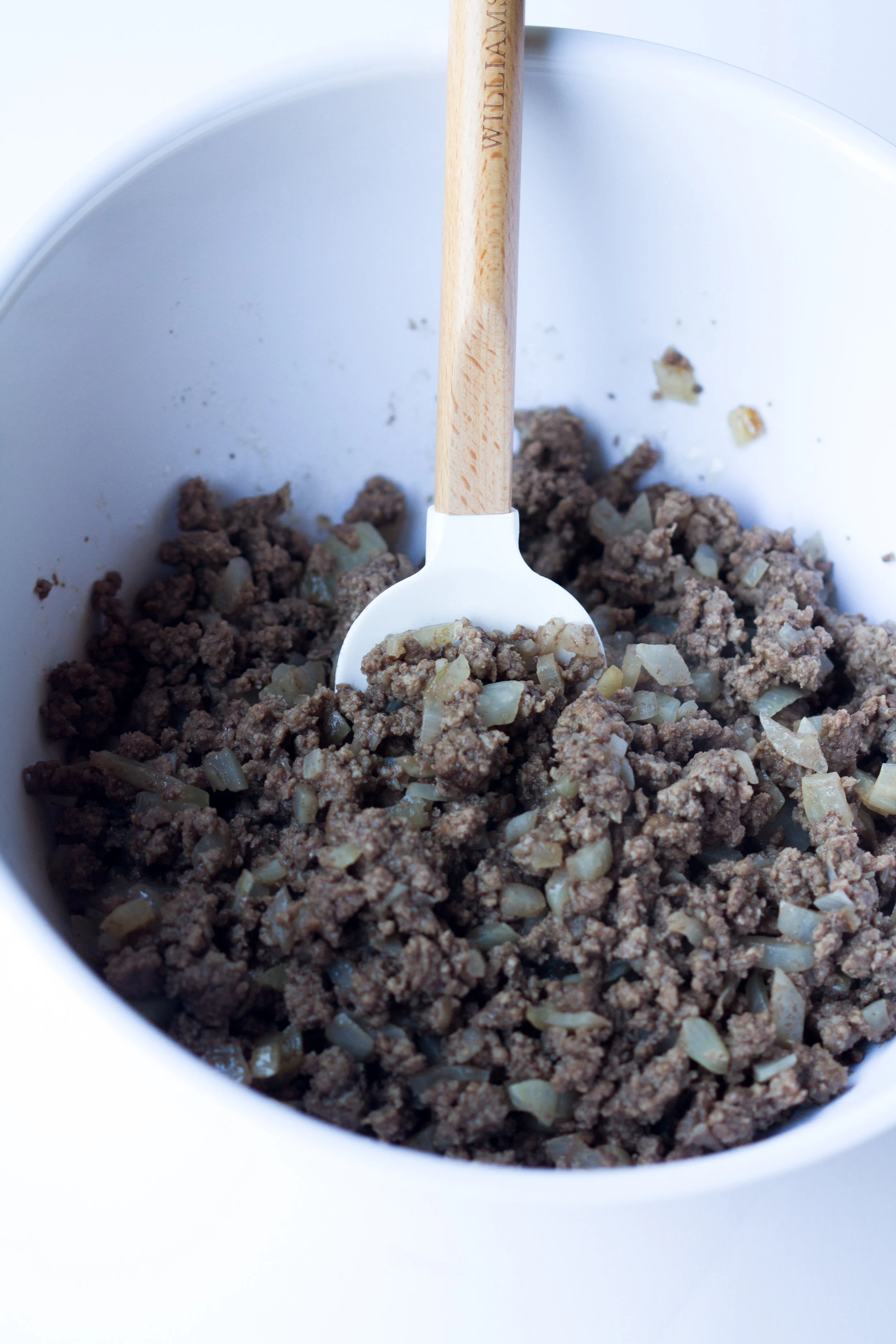 ground beef and onions with a wooden spoon