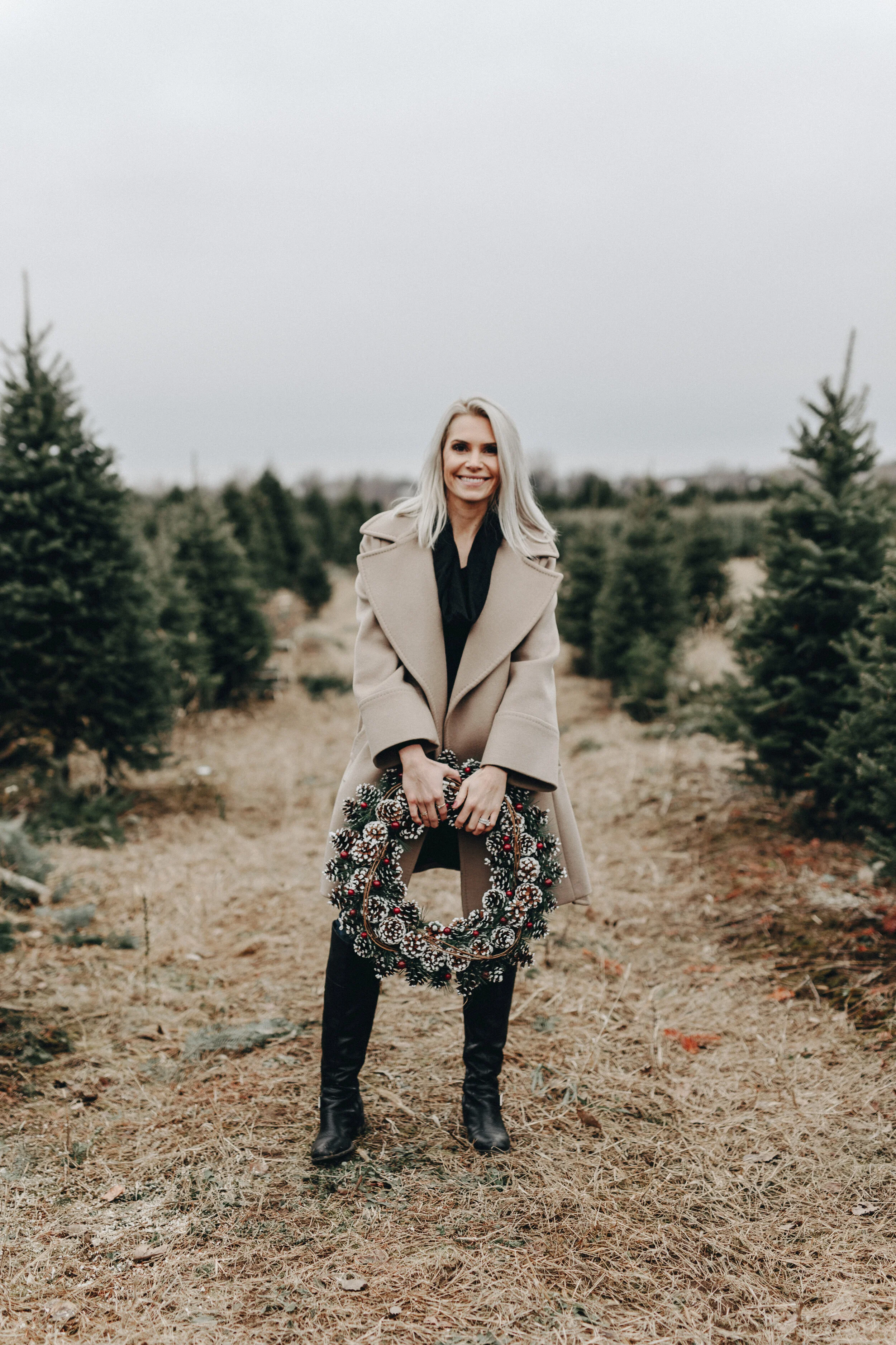 angela price holding a wreath in a christmas tree farm
