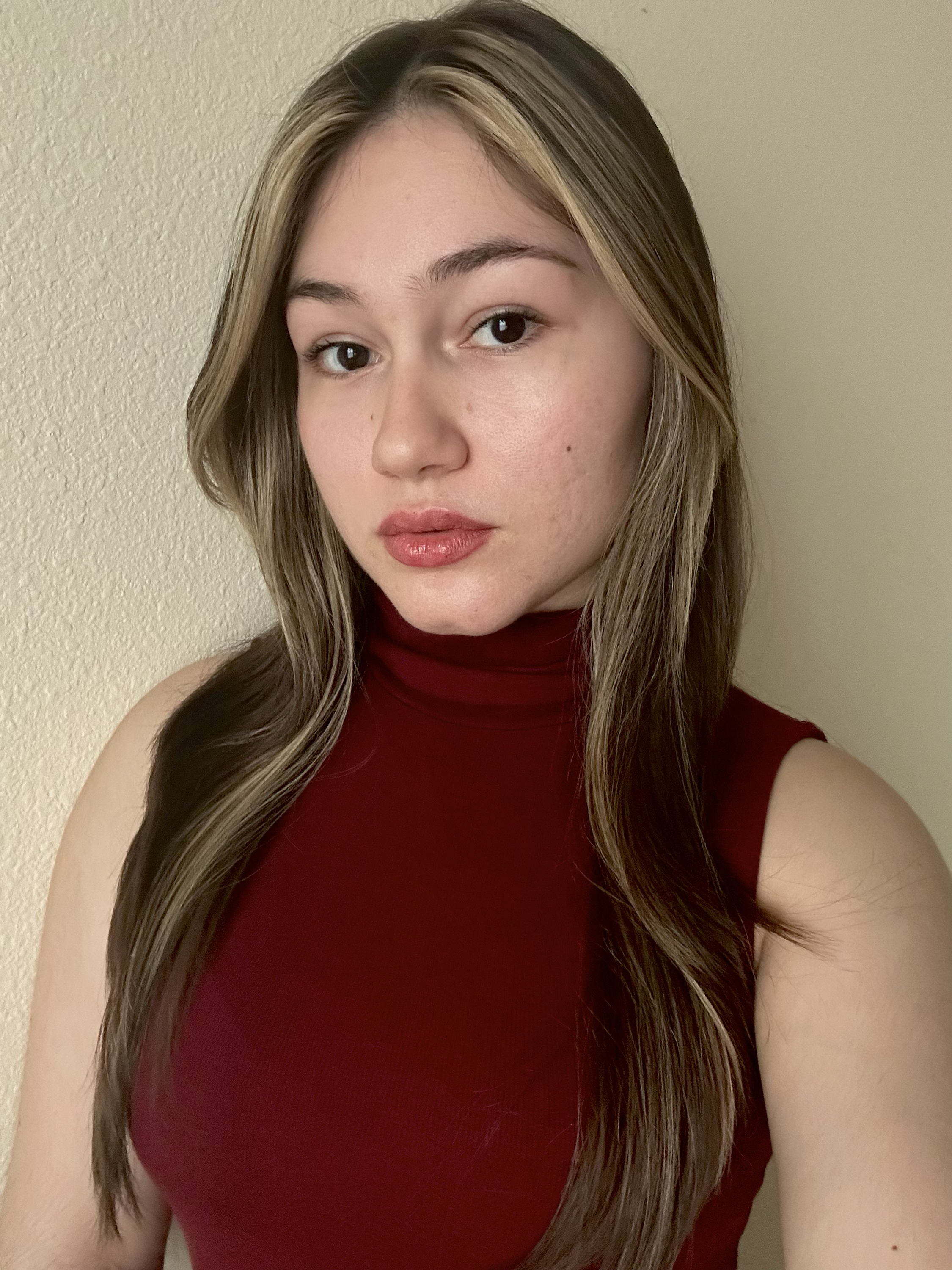 A woman with short, wavy brown hair, wearing a green blouse with a subtle polka dot pattern, smiling softly against a dark, blurred background.