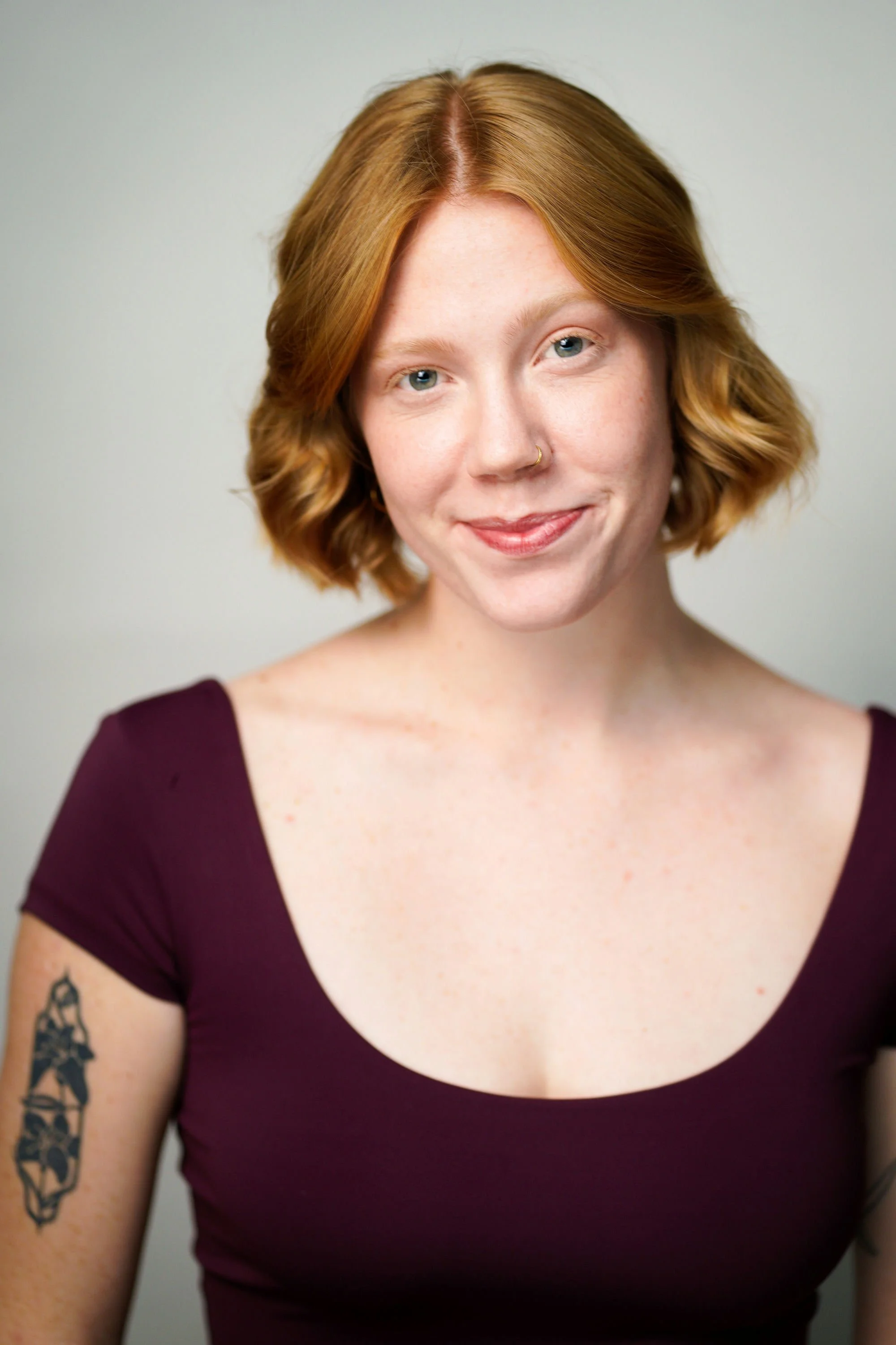 Portrait of a person with long dreadlocks, wearing a dark blue shirt, against a dark background.