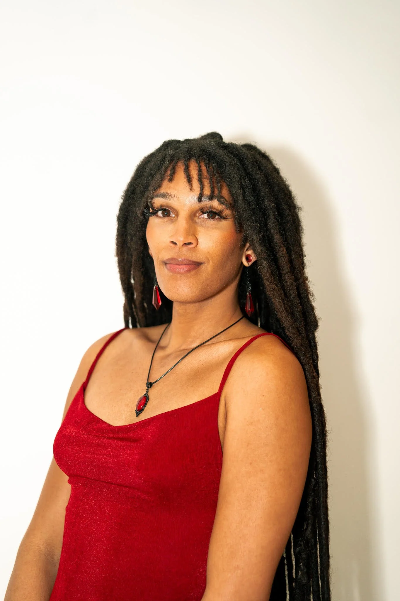 A woman with short, wavy brown hair, wearing a green blouse with a subtle polka dot pattern, smiling softly against a dark, blurred background.