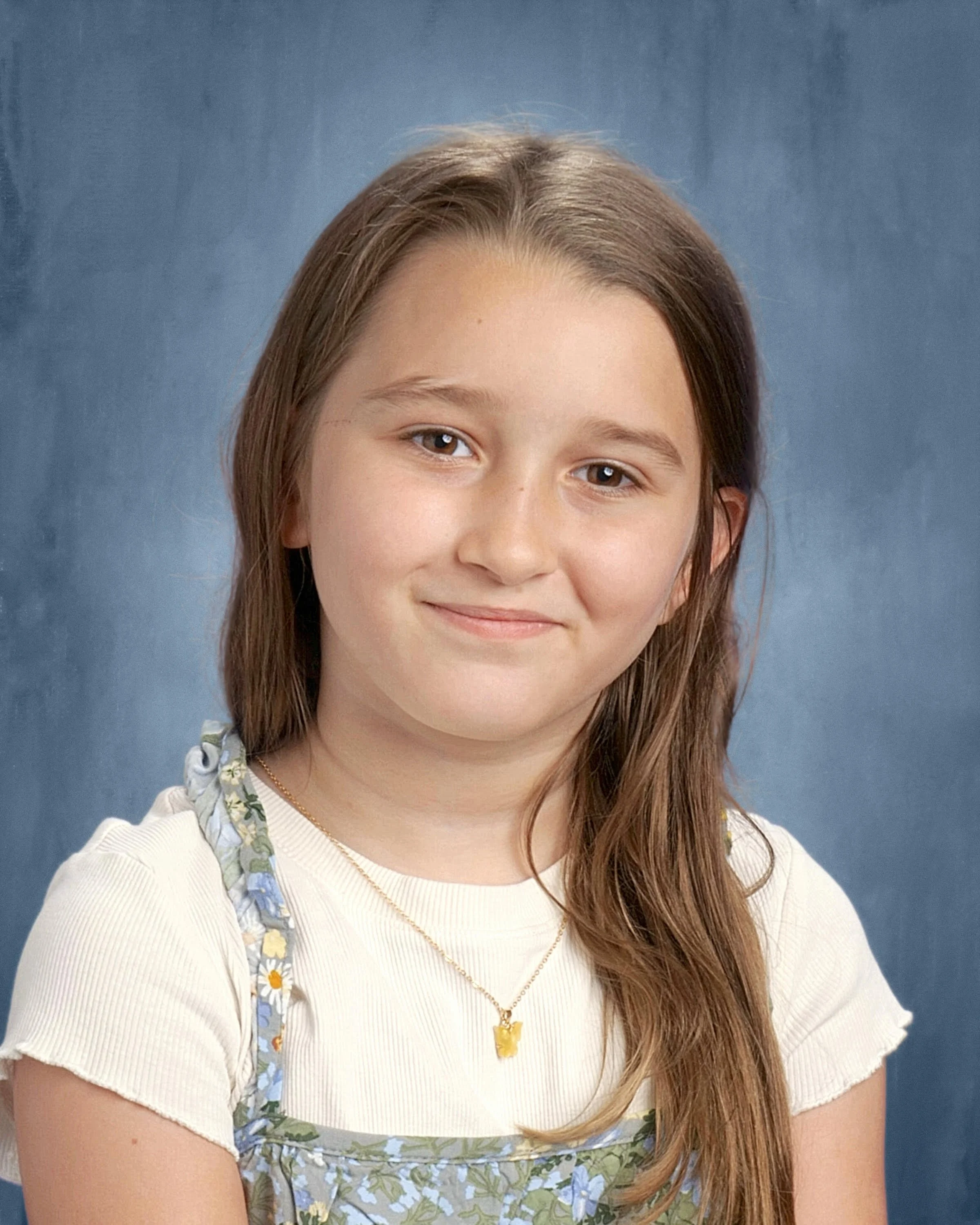 Portrait of a person with long dreadlocks, wearing a dark blue shirt, against a dark background.