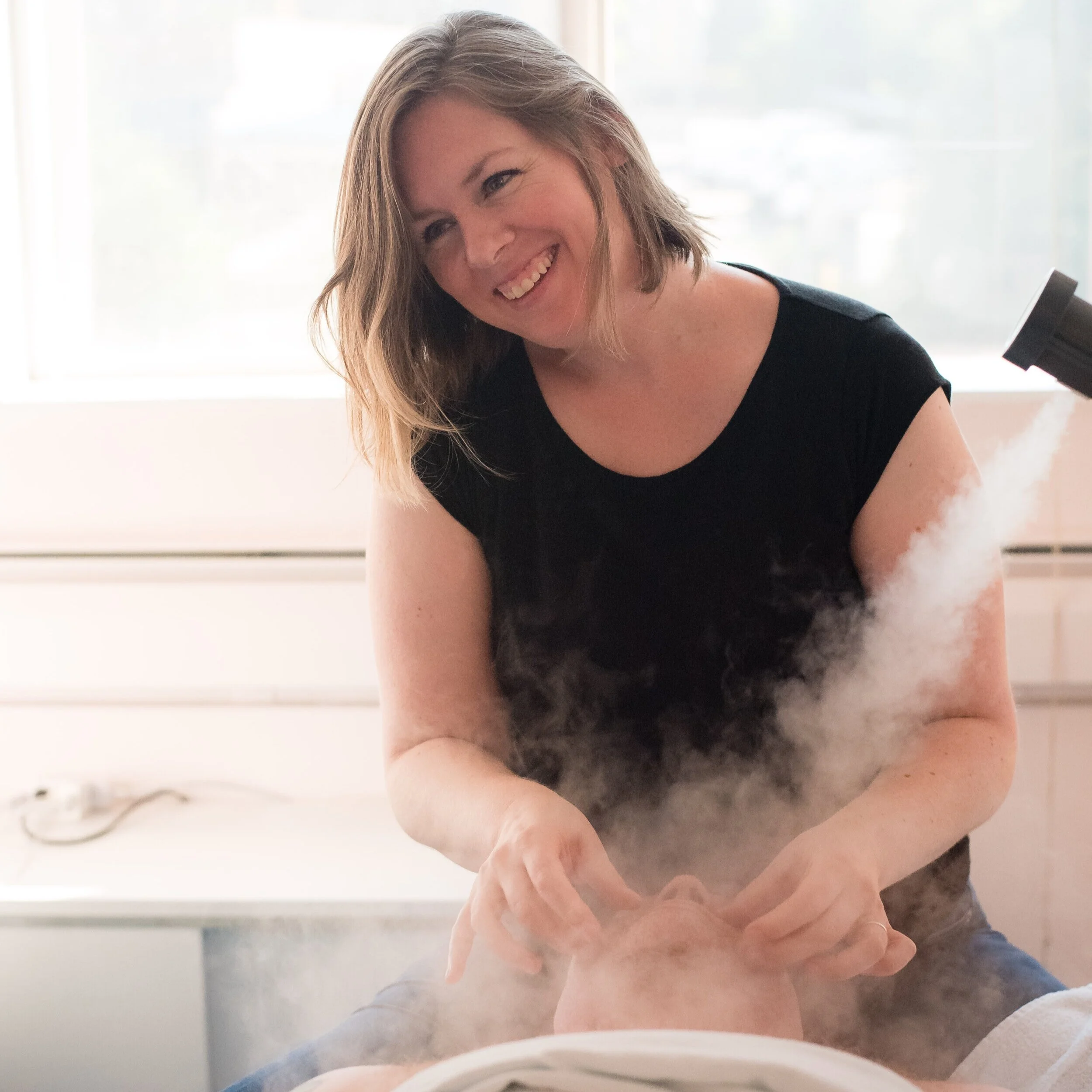 smiling woman massaging a face with steam