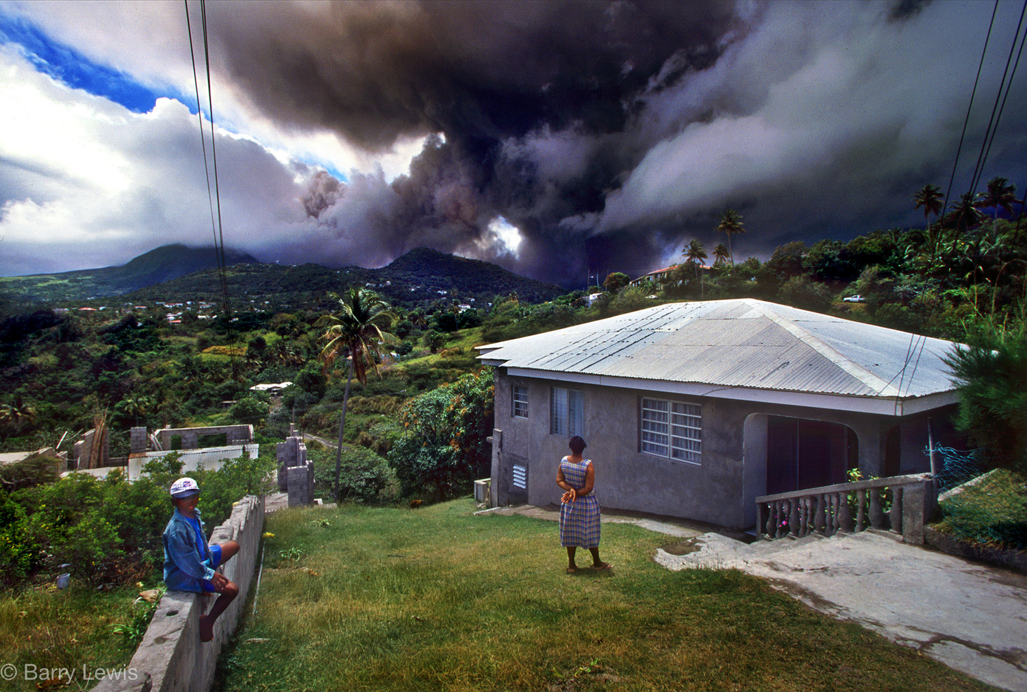  Family watching the eruption of  Chances Peak volcano in the Soufriere Hills, Monserrat, 1997.
Two-thirds of the population left Montserrat; the majority went to the UK.. 
