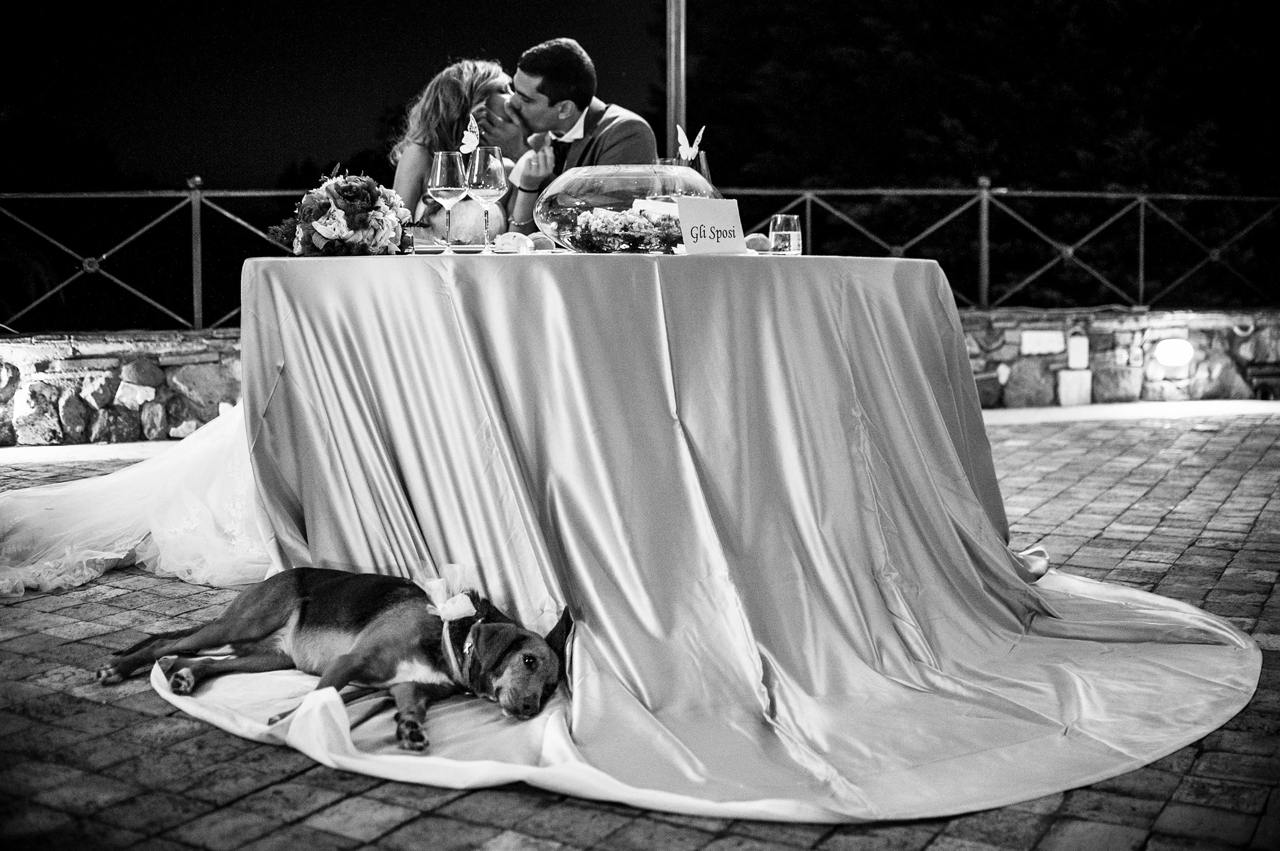 bride-and-grooms-dog-rests-under-nuptial-table-at-reception-black-and-white-wedding-photography.jpg