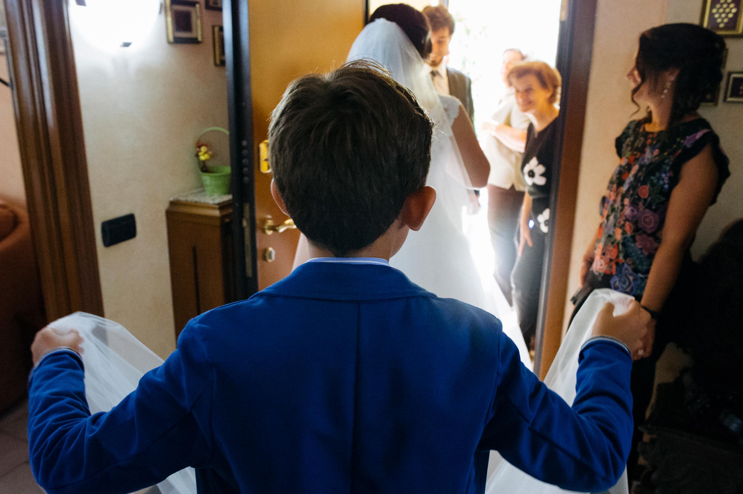 kid-holding-bridal-veil-helping-the-bride-going-out-of-home.jpg
