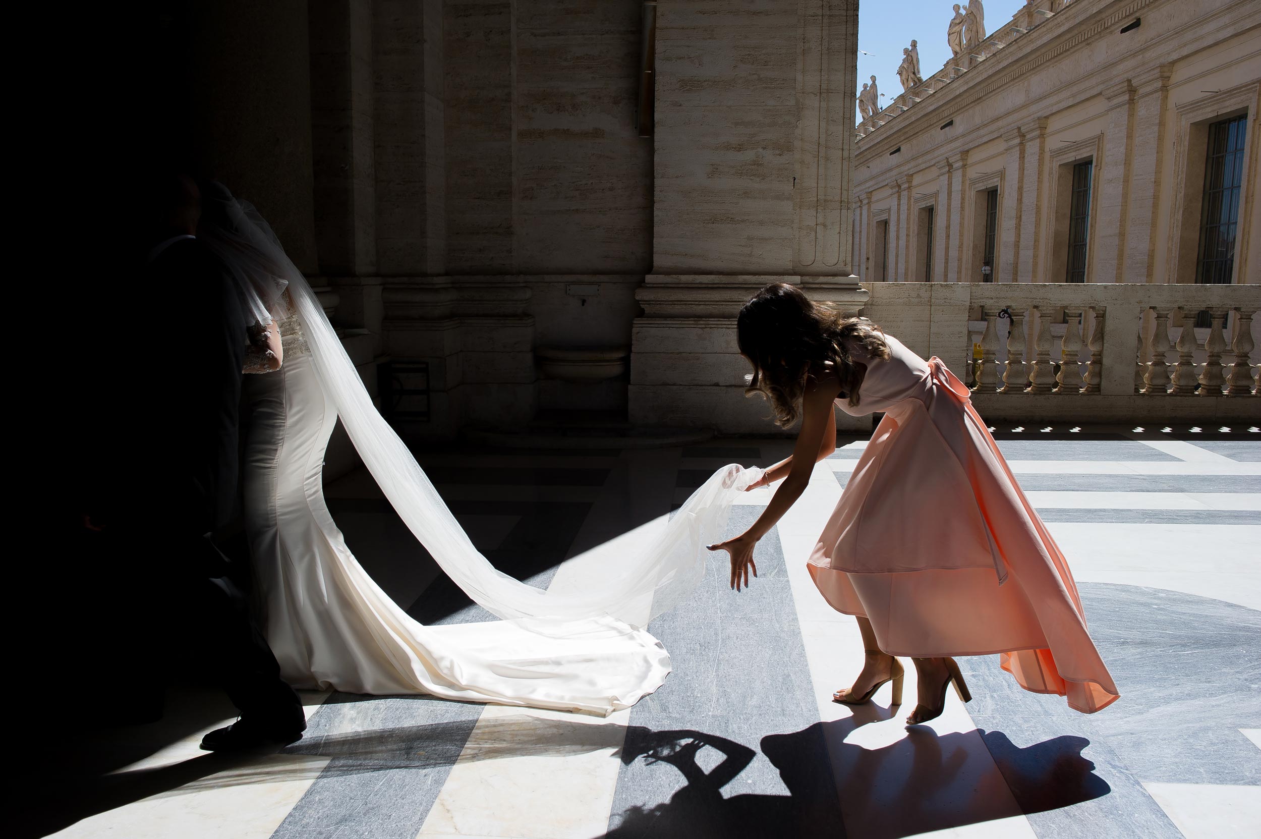 st-peter-basilica-wedding-in-vatican-silhouette-bridesmaid-helps-bride-holding-the-veil.jpg