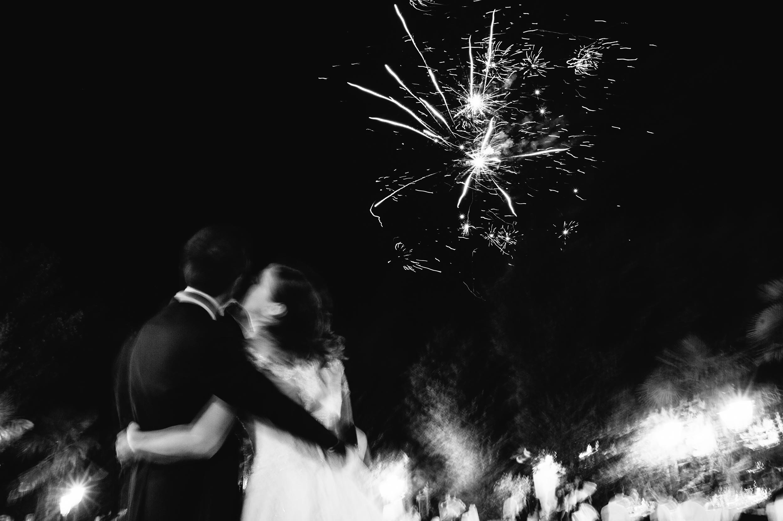 the-bride-kisses-the-groom-under-fireworks-black-and-white-wedding-photography.jpg