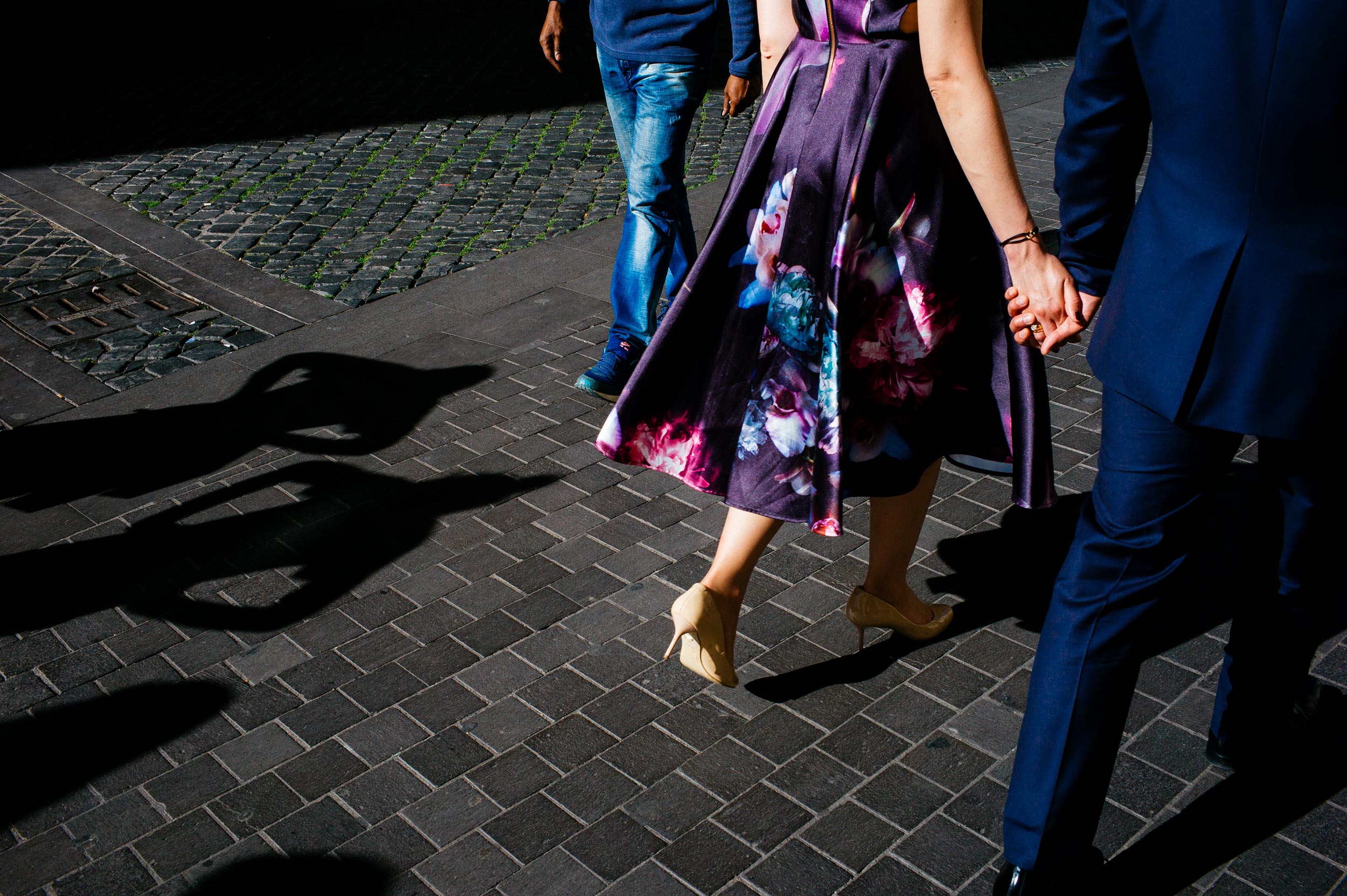 engagement-in-rome-couple-holding-by-the-hands-walking-the-shadow-of-two-passerbies-watching.jpg