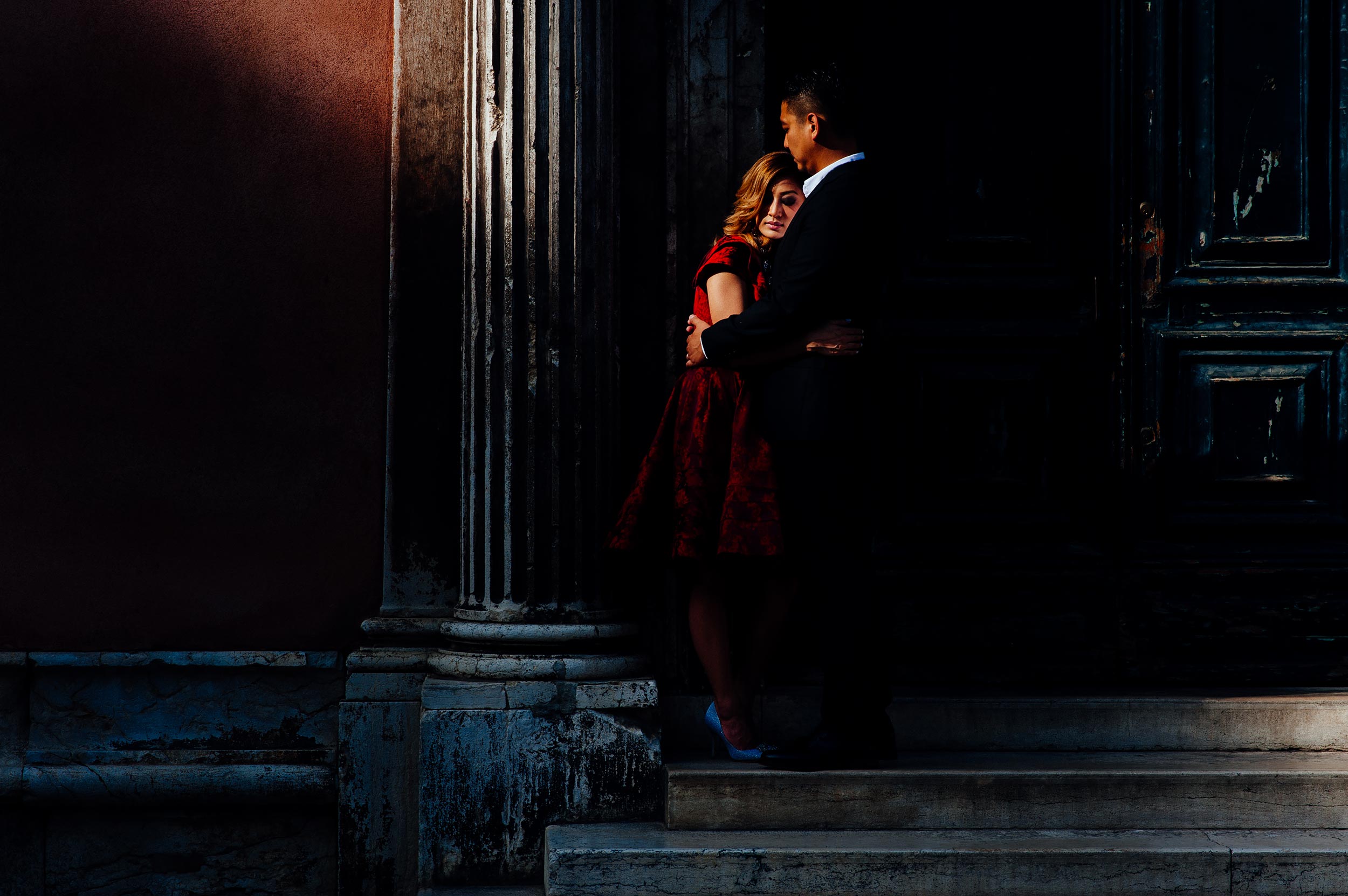 engagement-photographer-venice-couple-hugs-in-a-ray-of-light-red-dress.jpg