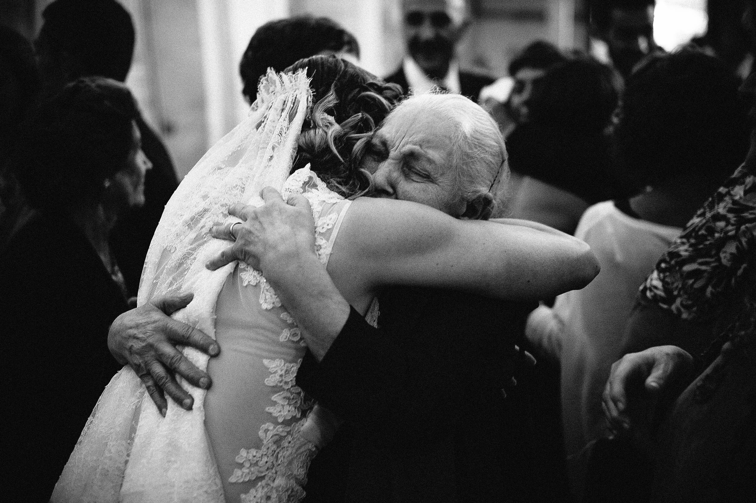 the-bride-hugs-her-grandmother-after-the-reception-italy-black-and-white-wedding-photography.jpg