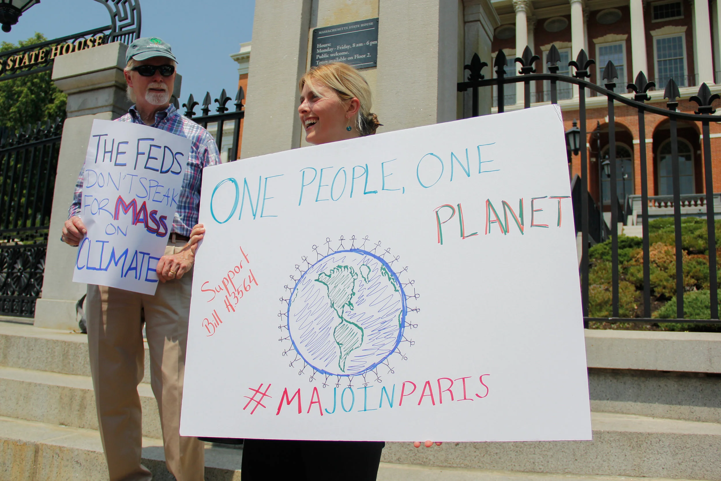 Rob Stenson, left, and Jessica Lambert show their support for the Paris Agreement outside the Massachusetts State House. Massachusetts has joined a coalition of states, known as the U.S. Climate Alliance, that have pledged to maintain the climate go…