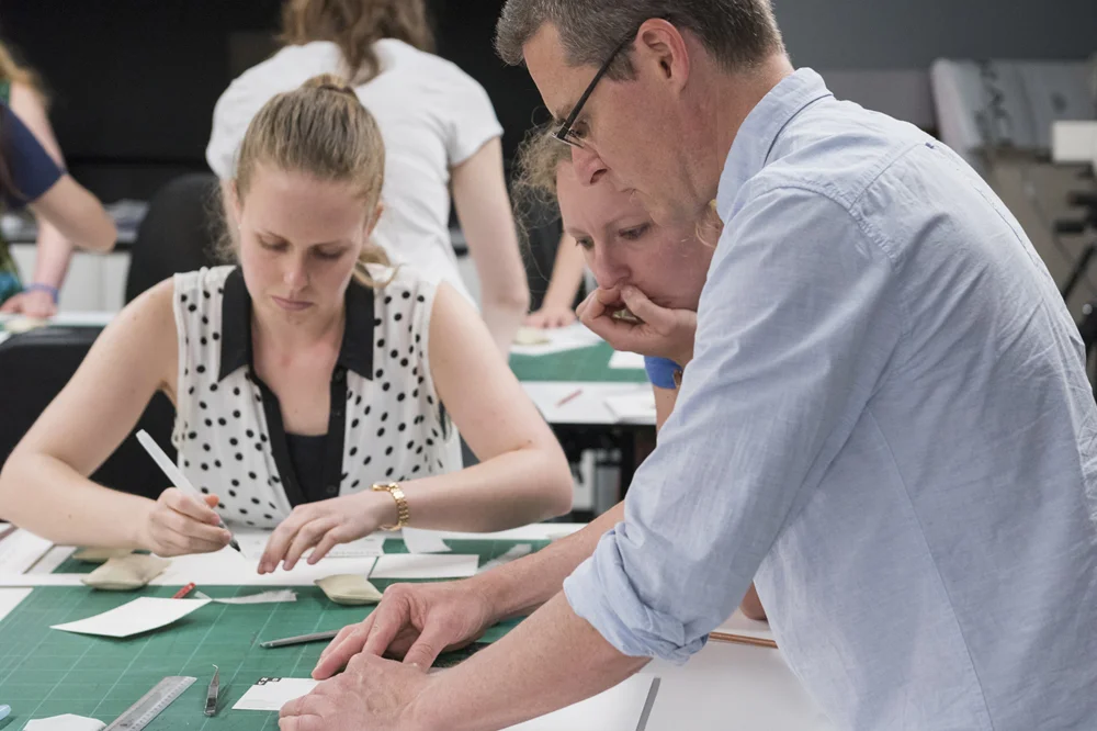 Paper conservator Peter Mitchelson demonstrates how to mount postcard with Elizabeth Gralton and Kate Ritchie 