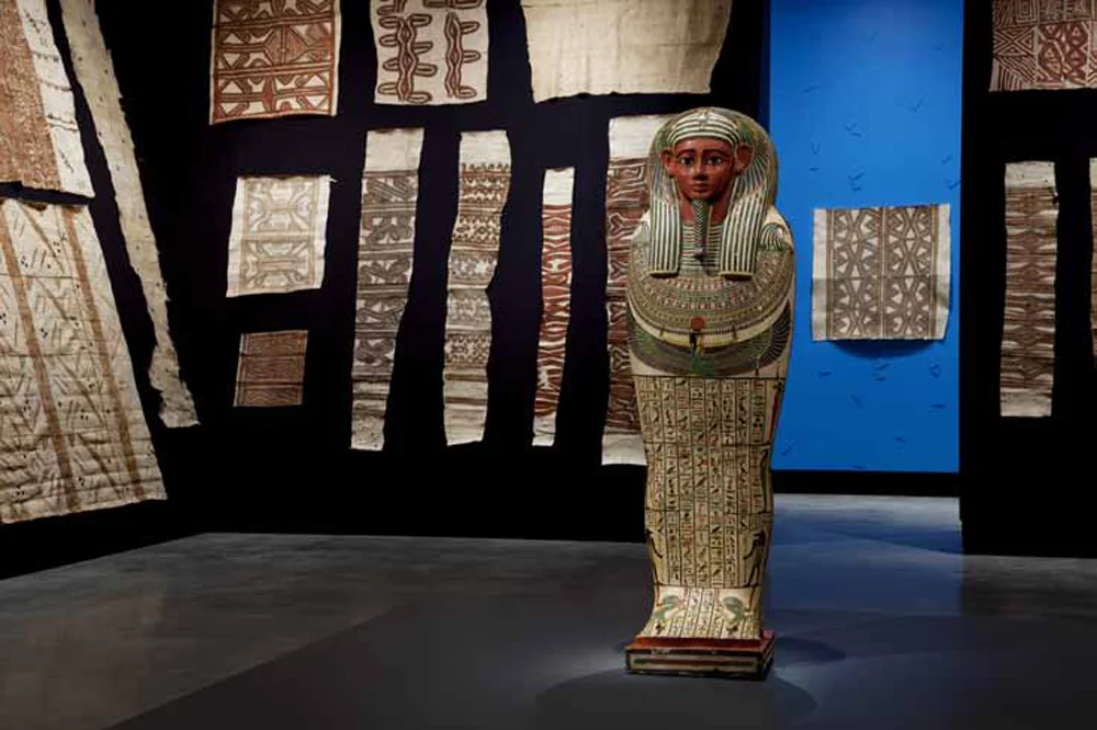 MONA’s 2012 exhibition Theatre of the World , which demonstrated a unique potential for collaboration by displaying over eighty Indigenous tapas from the TMAG collection alongside an Egyptian sarcophagus
