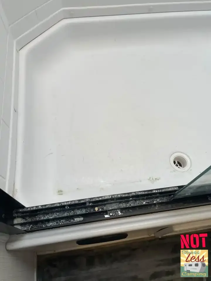 Broken glass on the floor of the bathroom from a shattered shower door.webp