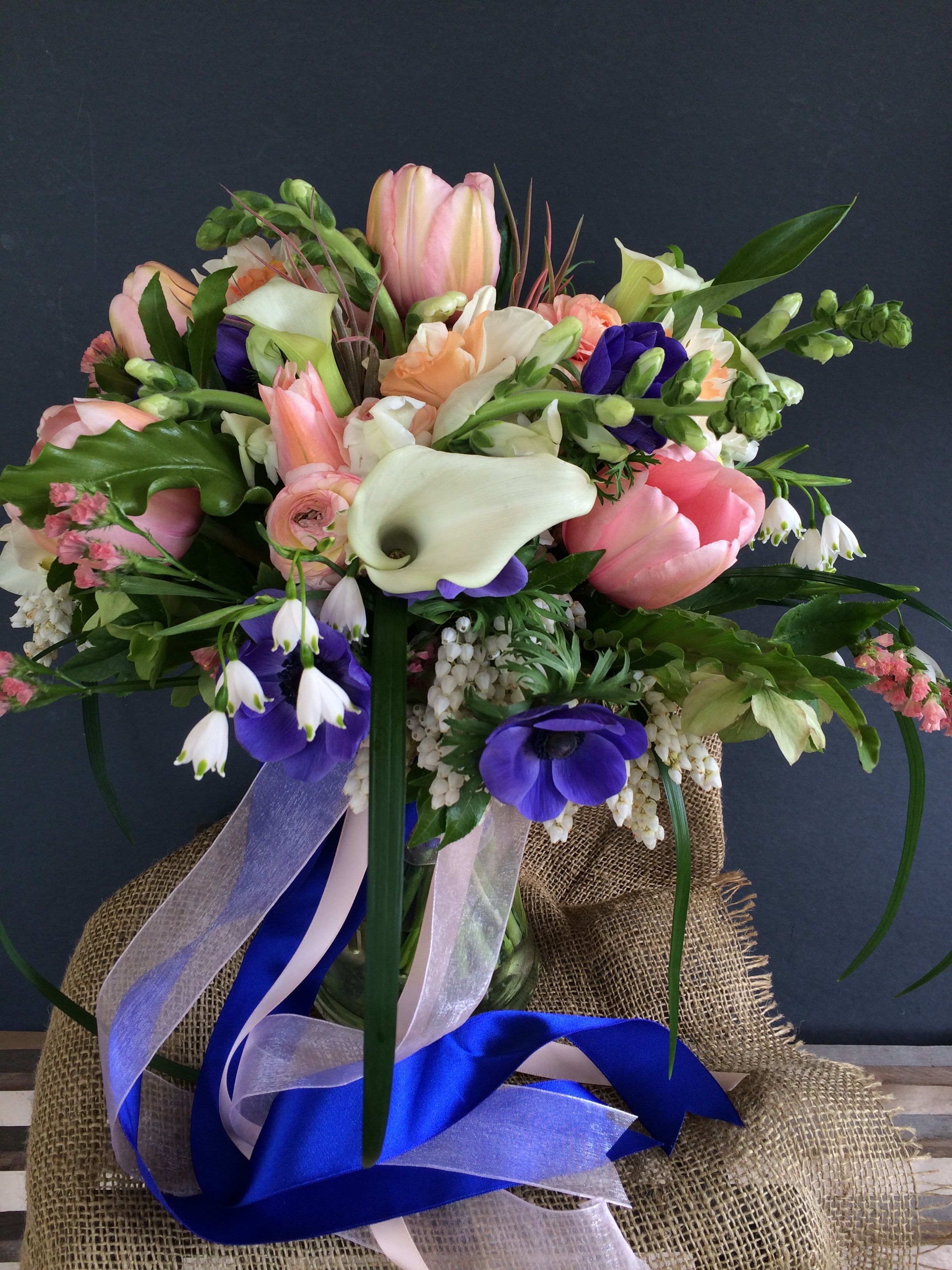 An early spring bridal bouquet of french tulips, peony, anemone, calla lilies and snow drops