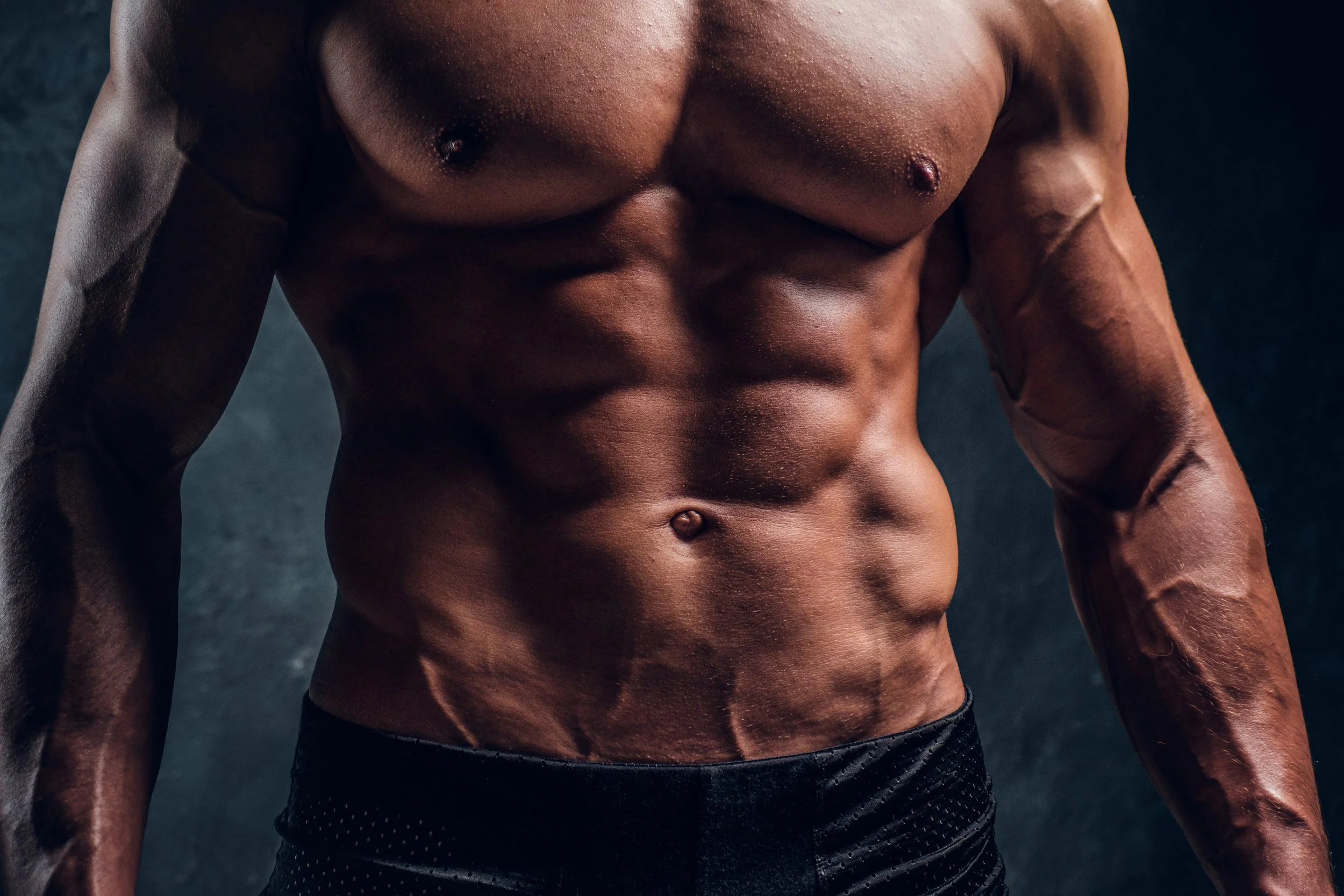 close-up-image-of-muscular-torso-with-dark-wall-ba-5T9B8MP.jpg