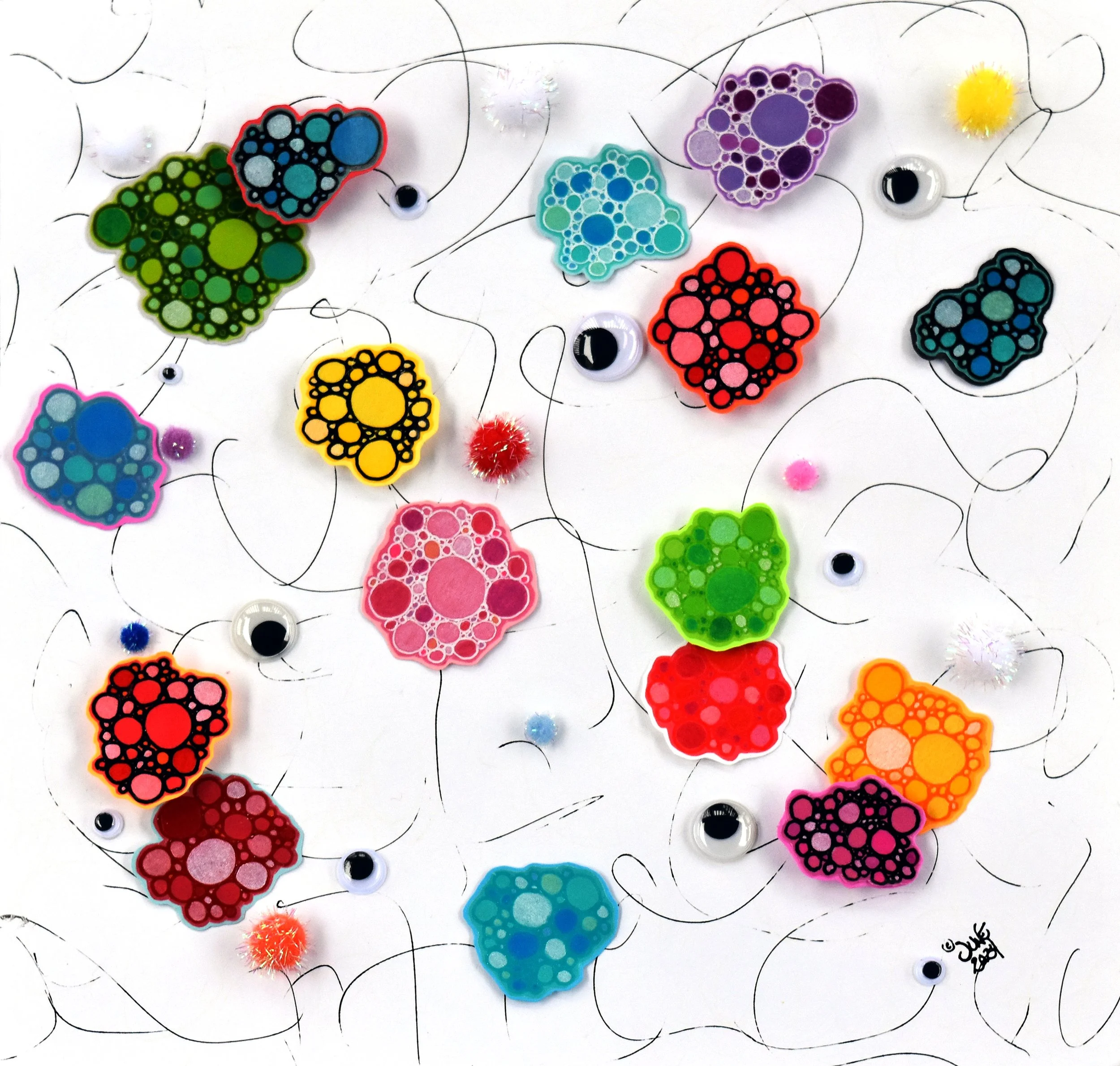 “Ishihara Eye Candy – Light” - Mixed Media (Colored Pencil; Glaze Pen; Gel Pen; Colored Vellum Paper; Foam; Wiggly Eyes; Glitter Pompoms on Scrapbooking Paper) 12” x 12” x ½”. 2024. Photo: June Krinsky-Rudder
