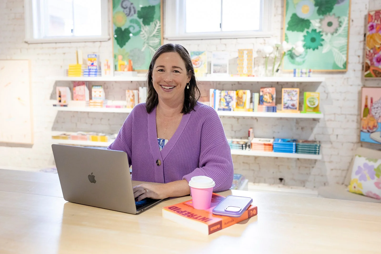 Paula Bridges, founder of Studio Chevell, working on brand storytelling with laptop and books in a creative studio space.