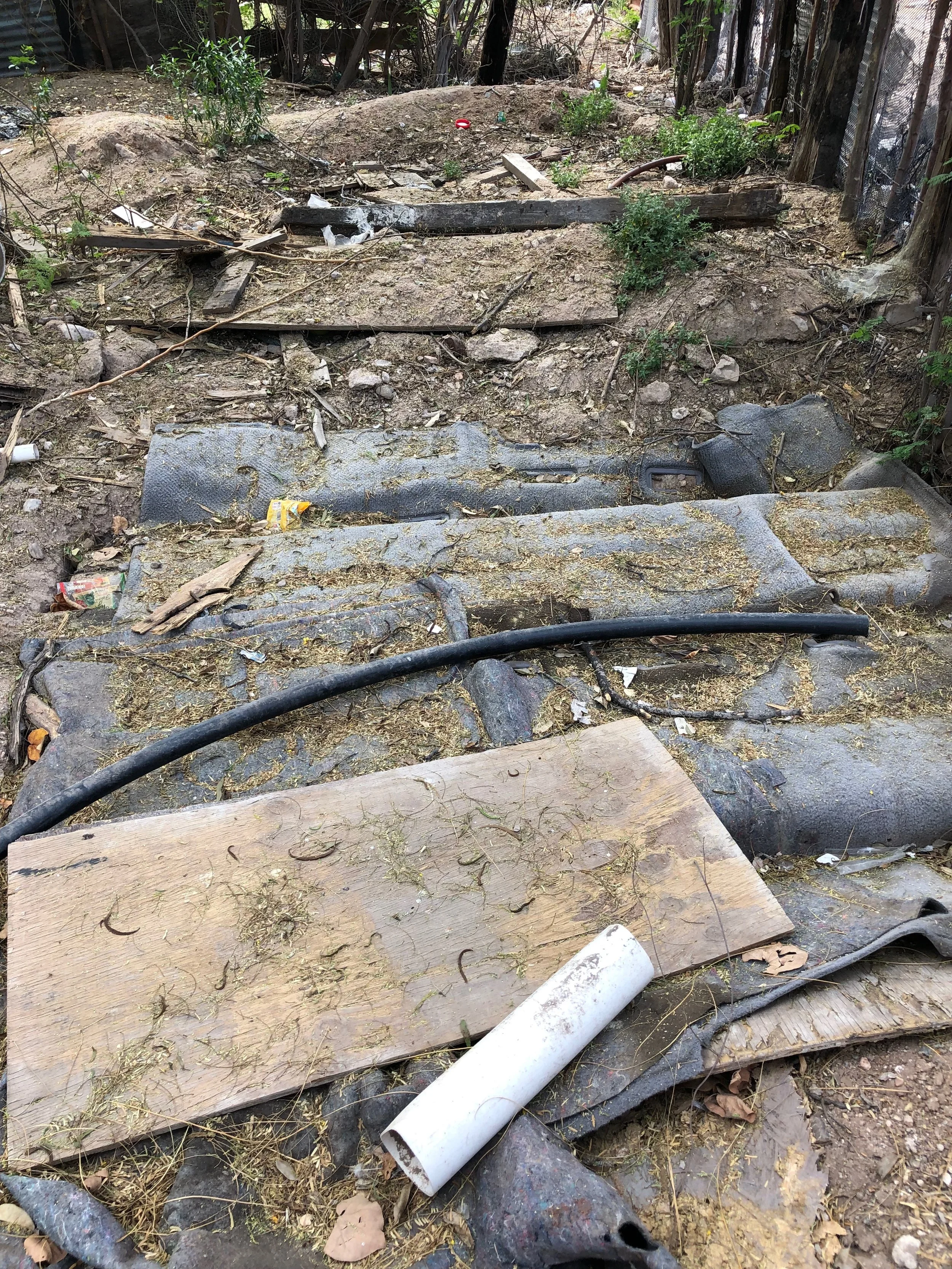 You can see that the septic field is covered with light materials. Also, the existing outhouse is falling apart and full of waste.