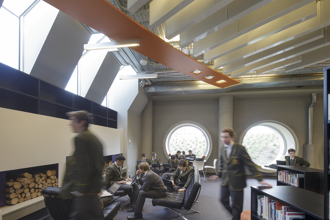  A cosy and intimate reading lounge sits at the base of the building with a fireplace below skylight windows that punch light deep into the interior space. Big circular reading windows provides a space for students to read and relax whilst gazing out