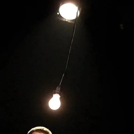 Ampoule électrique suspendue au plafond, éclairant dans l'obscurité.