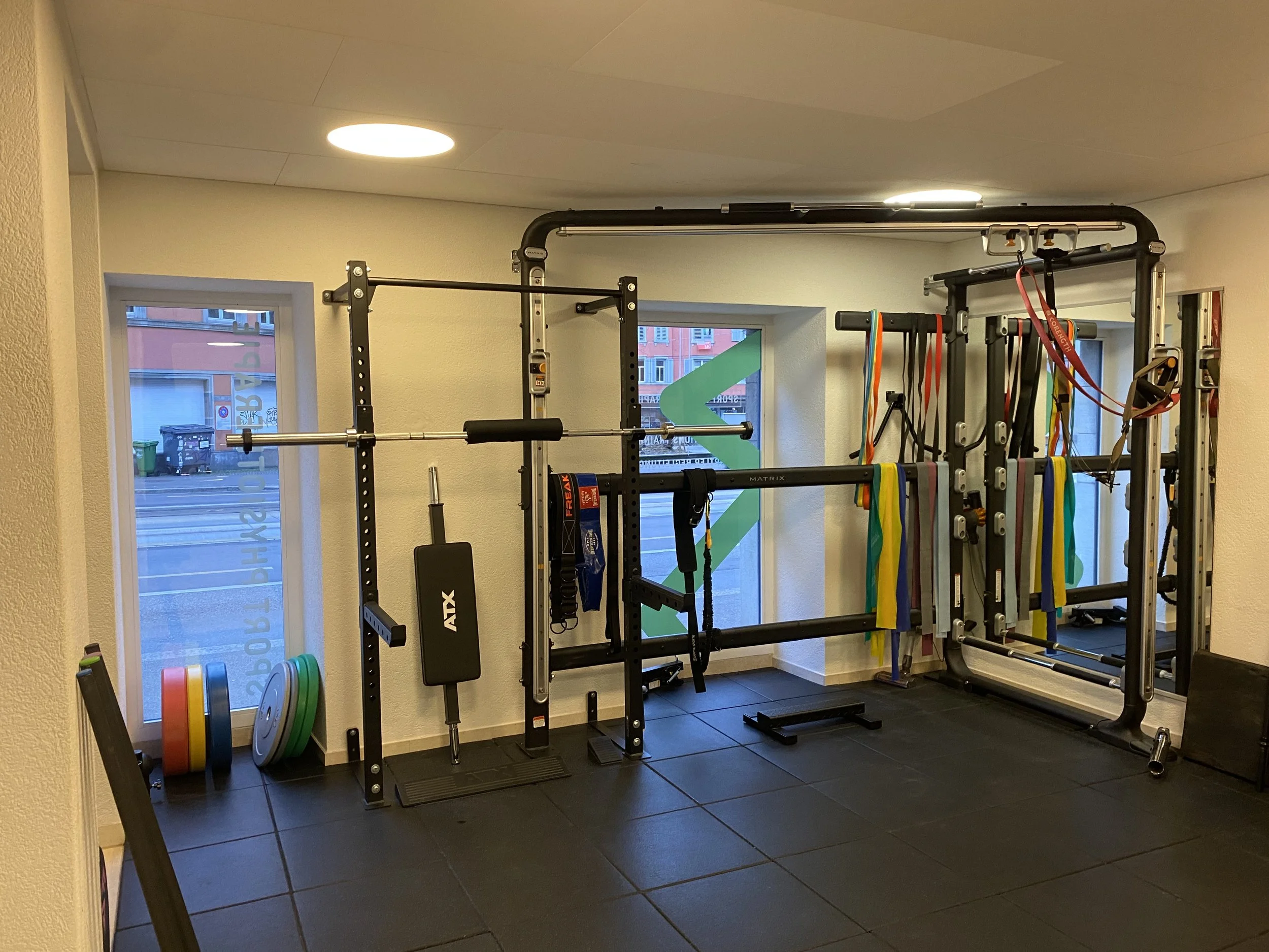 Innenraum eines Sport Physio Praxis mit verschiedenen Kraft- und Ausdauergeräten, Hanteln und Gymnastikbändern.