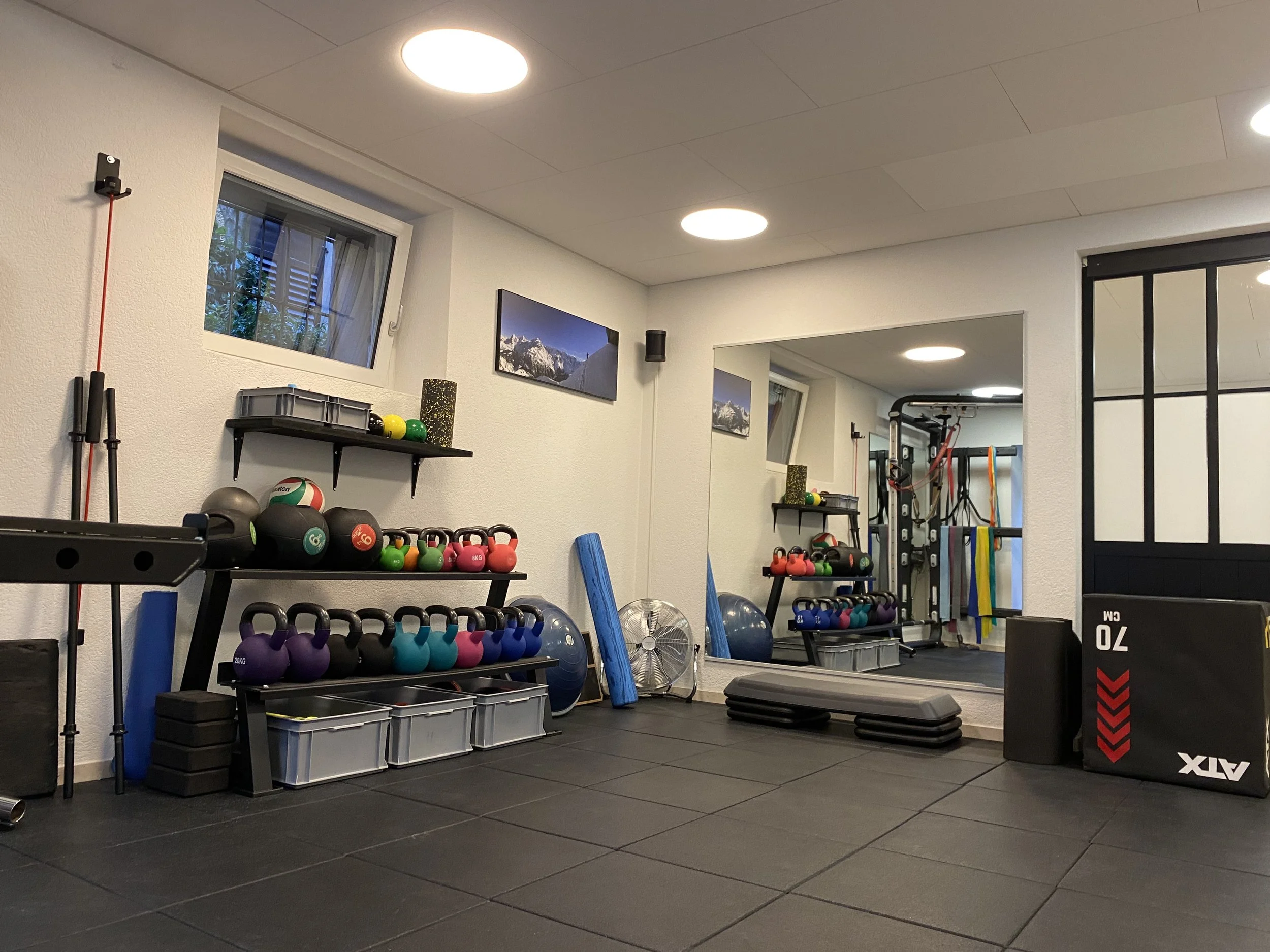 Innenraum eines Physio Praxis mit Hanteln, Gymnastikbällen, Matten, einem Spiegel und Trainingsgeräten.