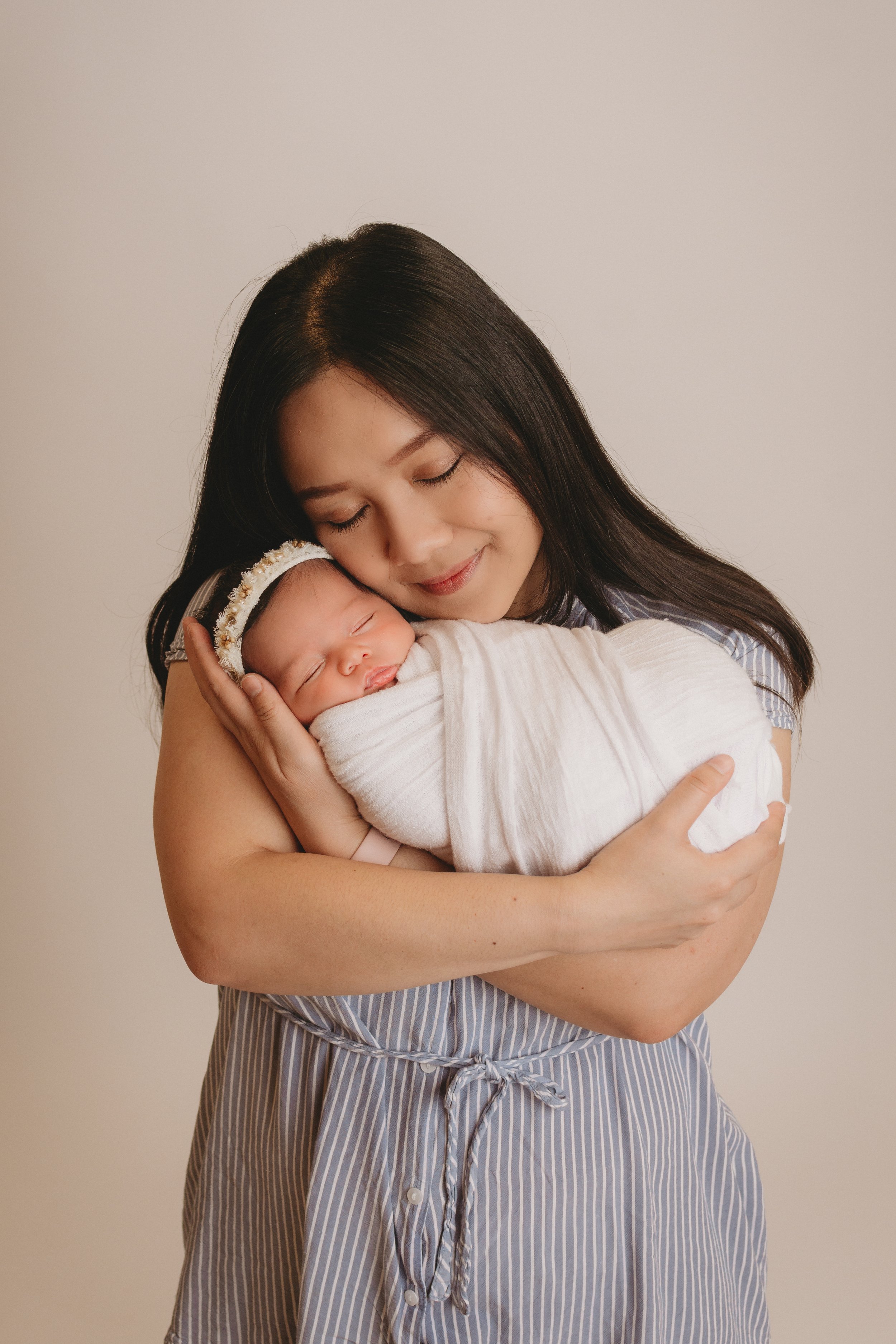 Mommy holding newborn baby wrapped up