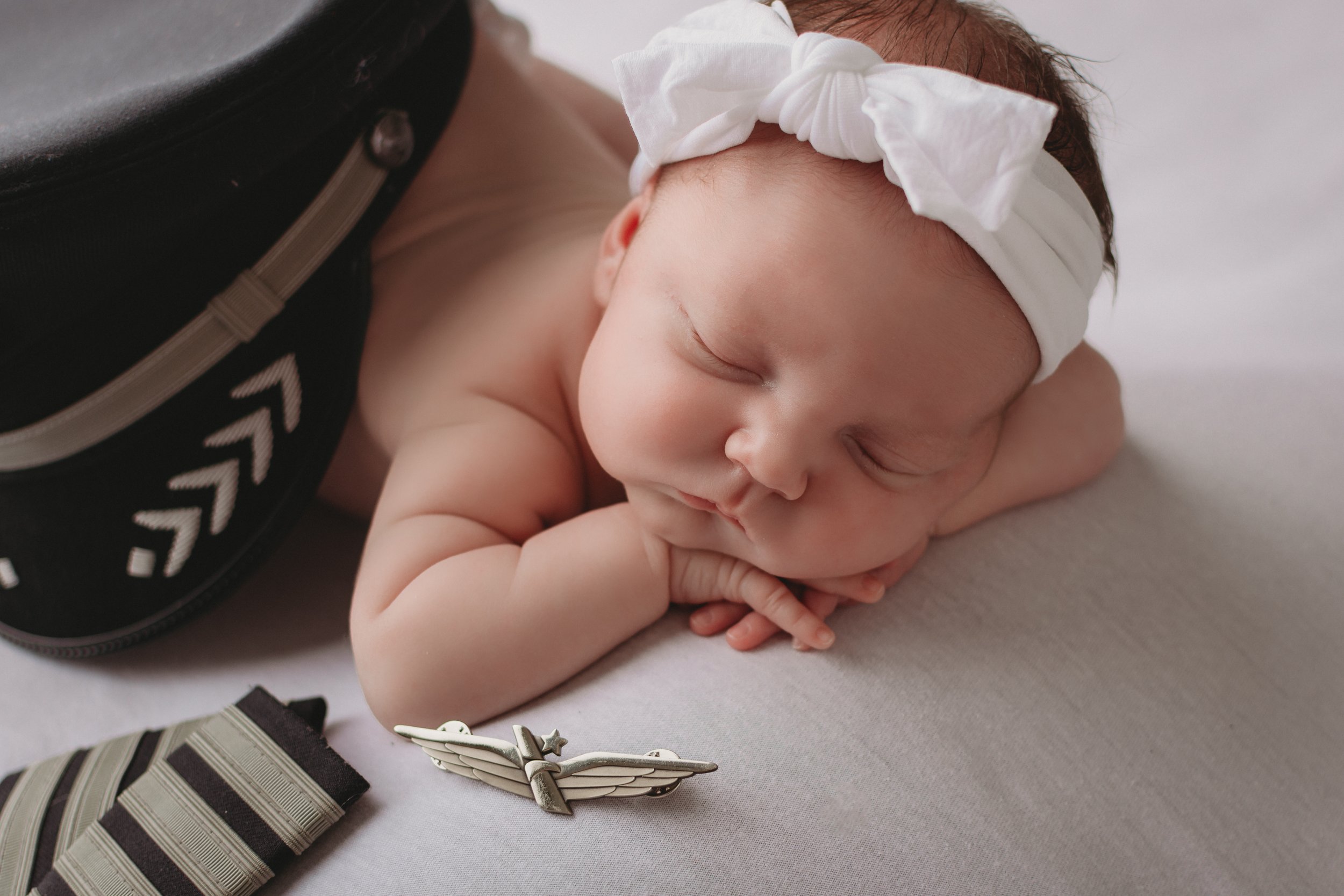 Newborn baby girl with dad's pilot hat