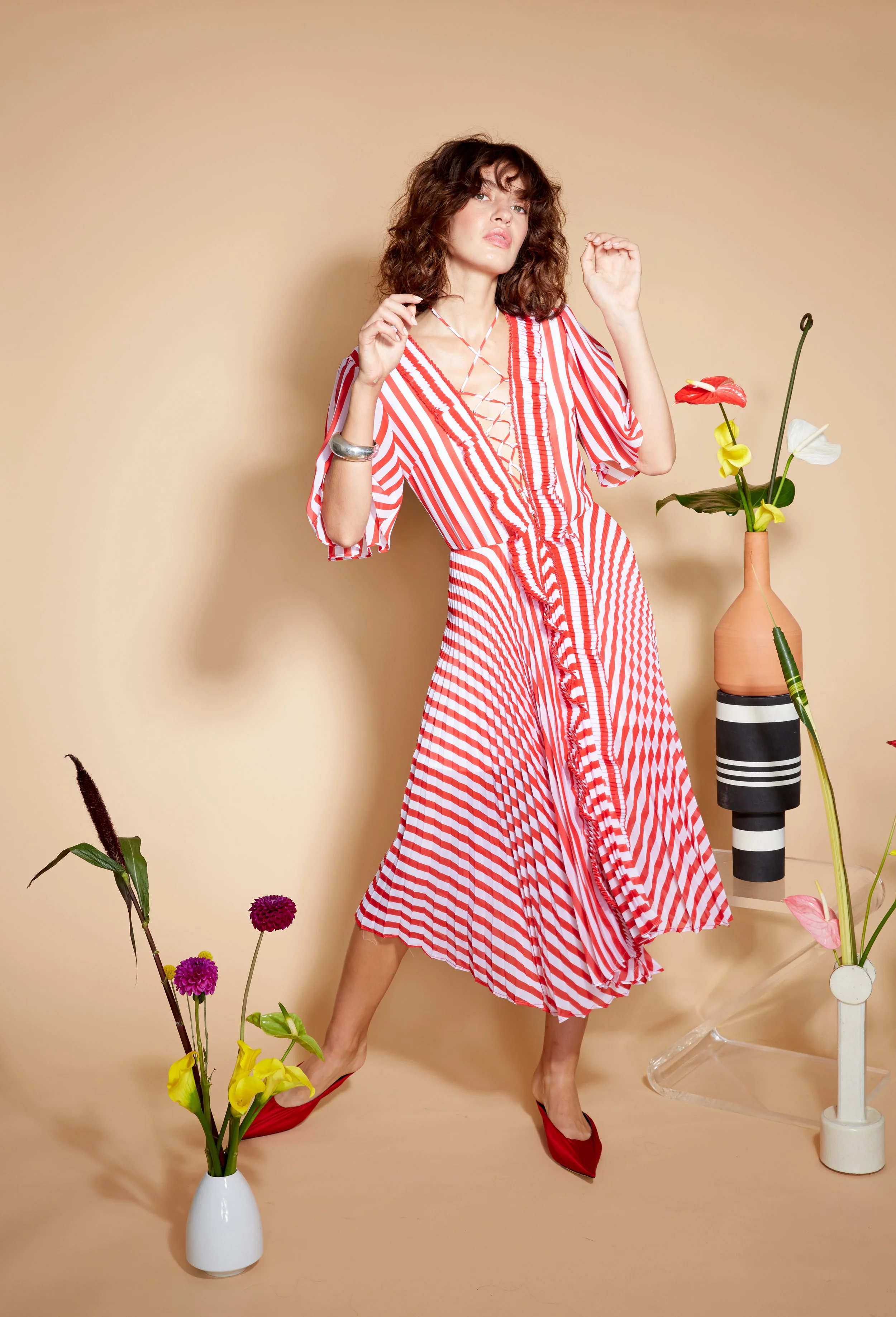 Model stands in red and white stripe short sleeve dress with v neckline and pleated trim