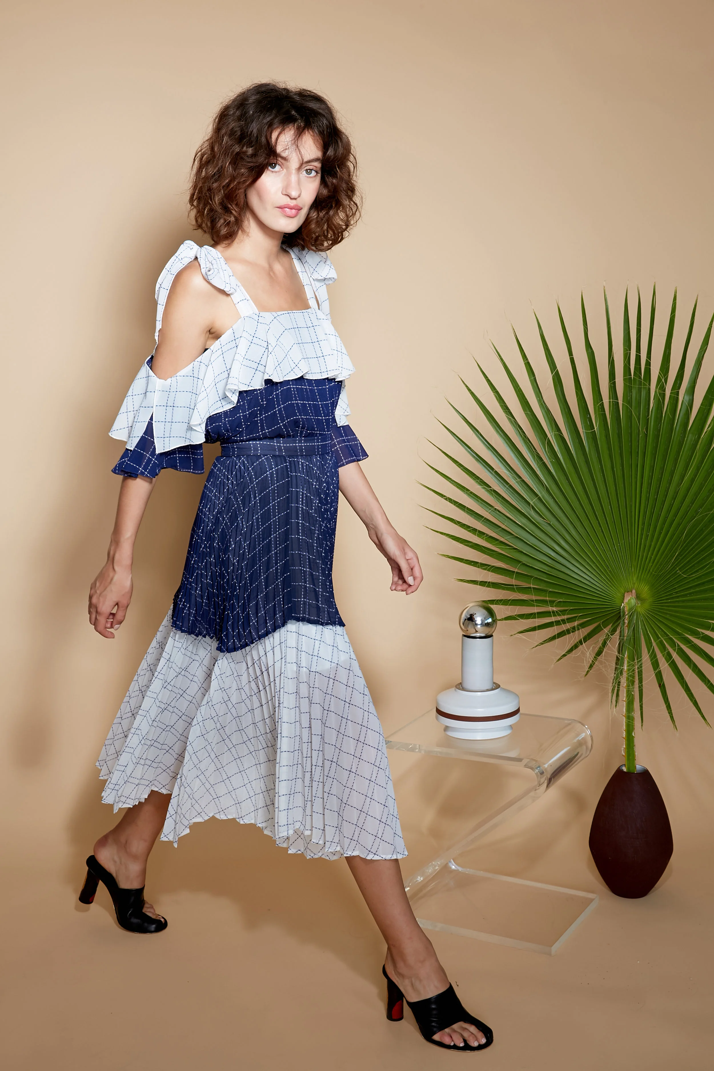 Model walks in cold shoulder short sleeve navy and white color block blouse and skirt