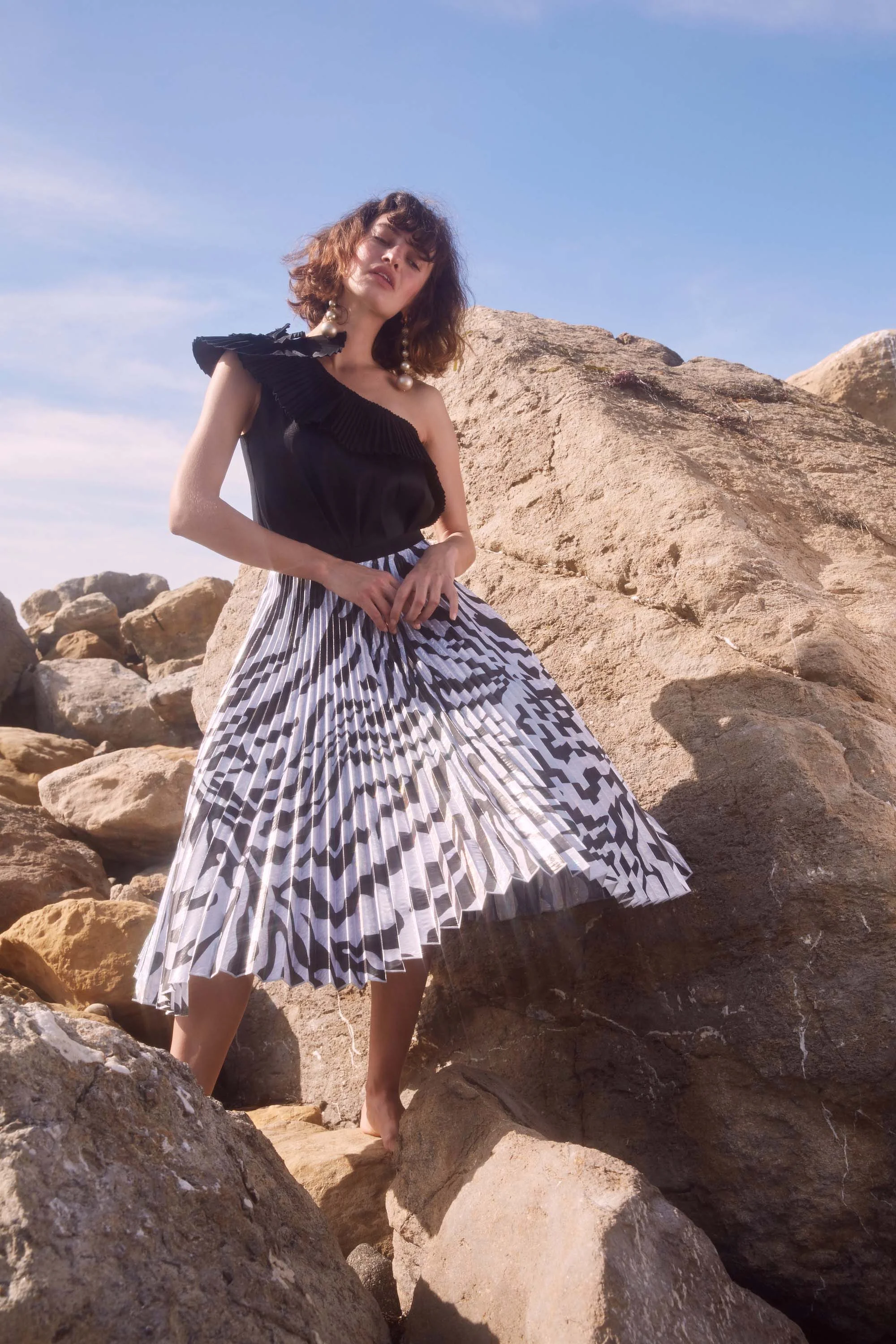 Model stands on rocky beach in Clara iridescent zebra print skirt