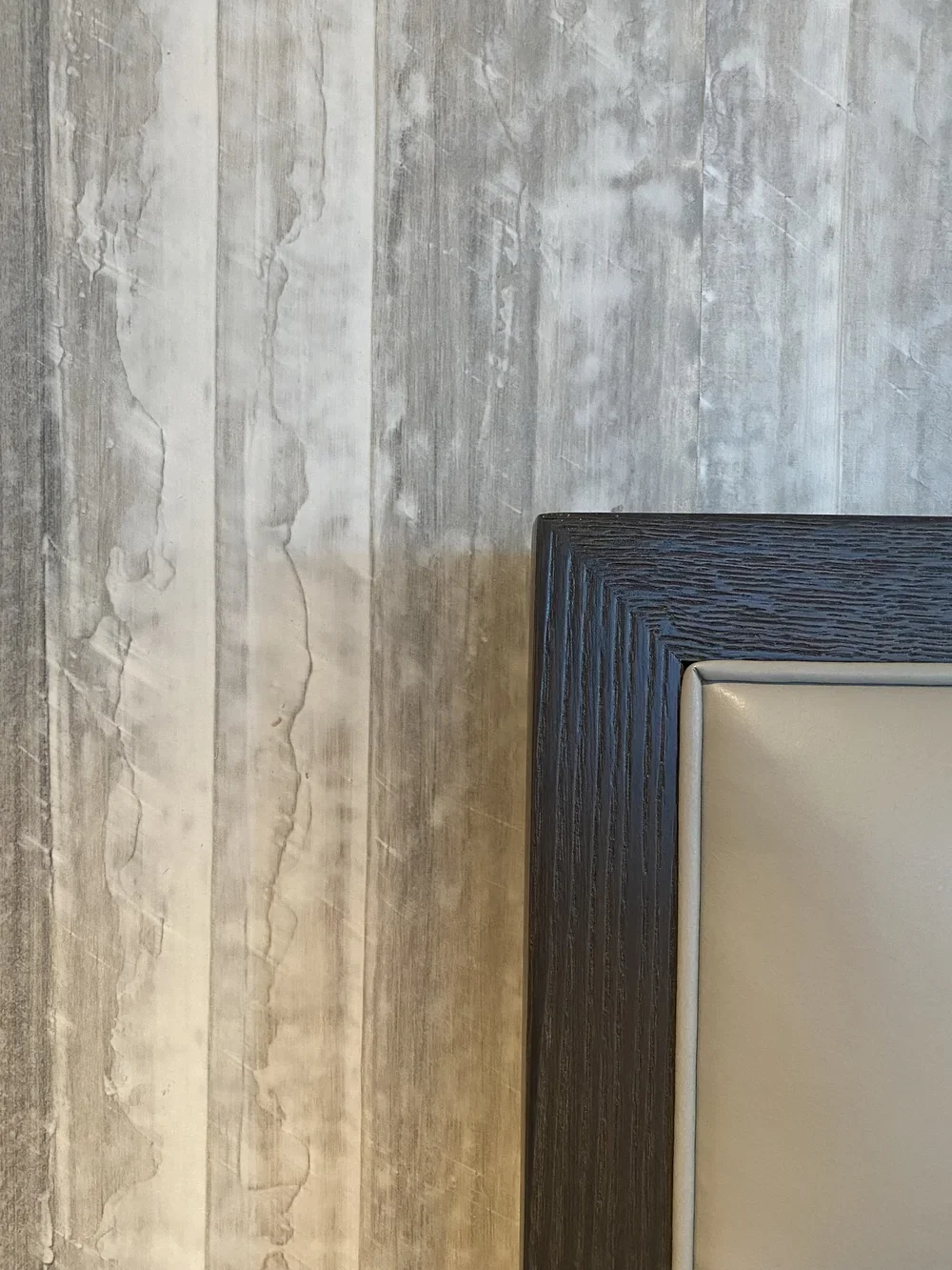 Interior_of_Sea_Mist_Home_in_Carmel_Showing_Edge_of_Bedframe_Blending_in_With_Grey_Textured_Walls.webp
