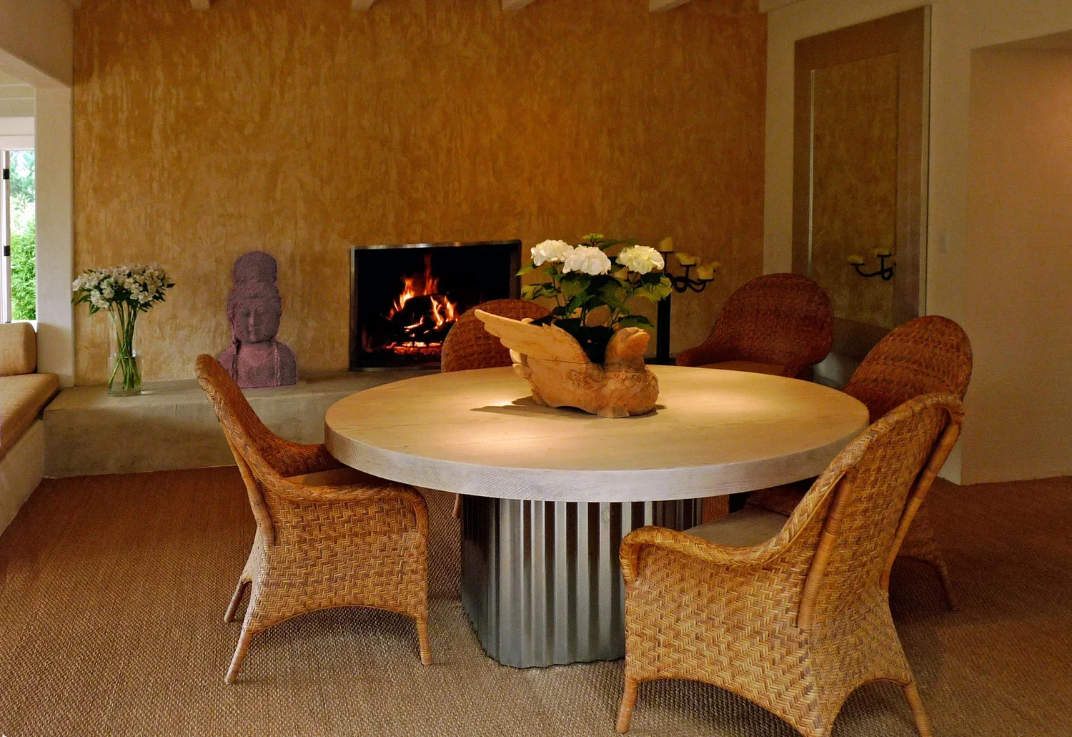 Interior_of_Carmel_Valley_House_Showing_Dining_Table_With_Wickered_Chairs_Stone_Tabletop_and_Fireplace.webp