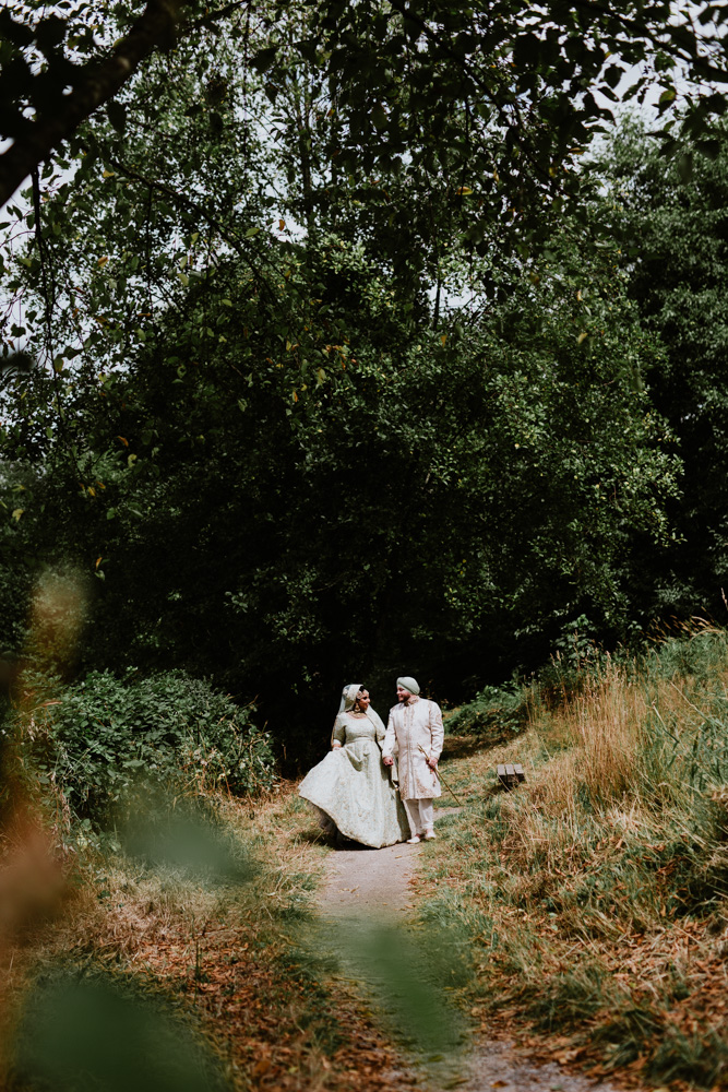 indian bride and groom walking through forest