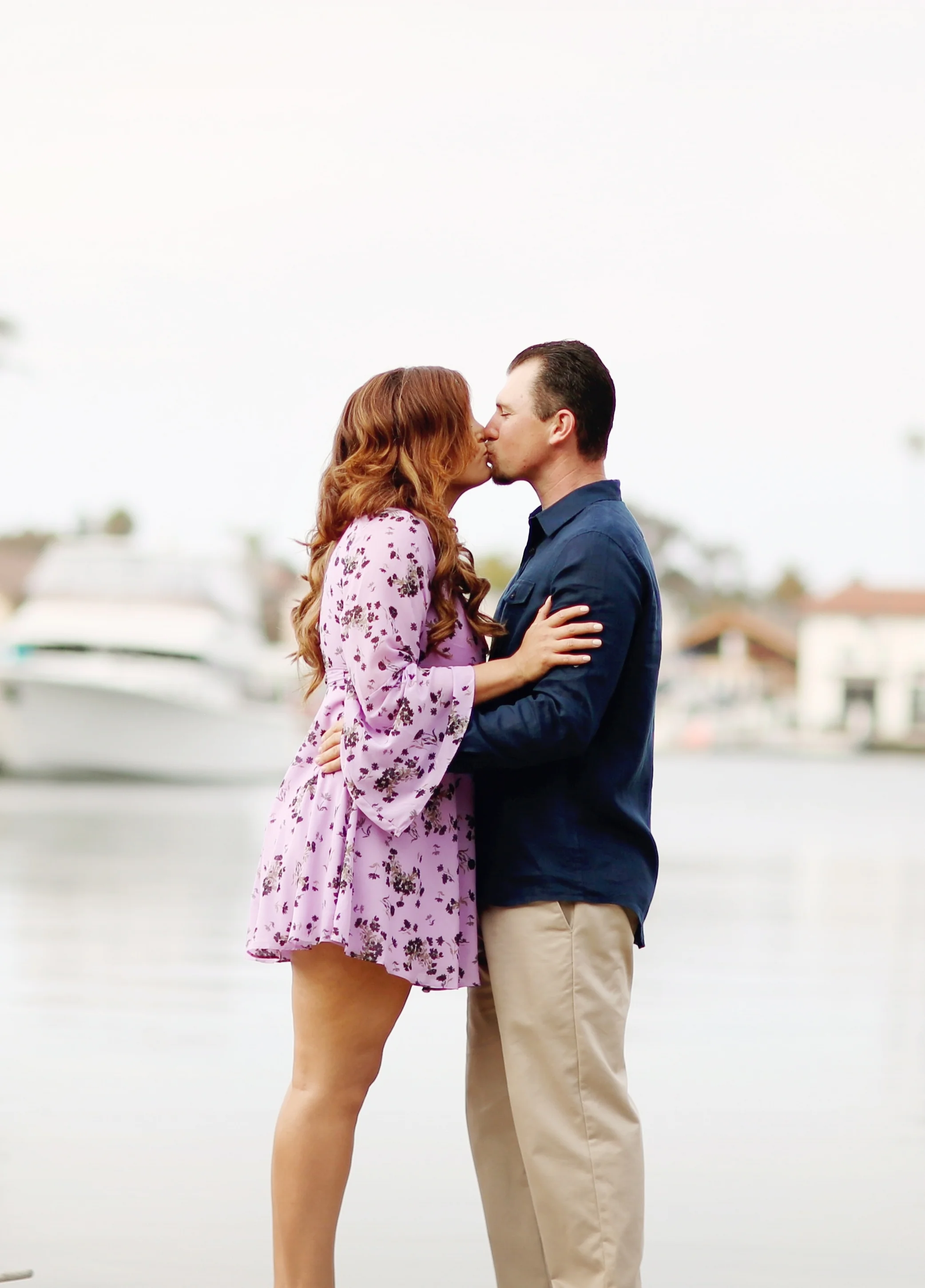 Boats, beach, engaged couple kissing in this beautiful beach portrait.