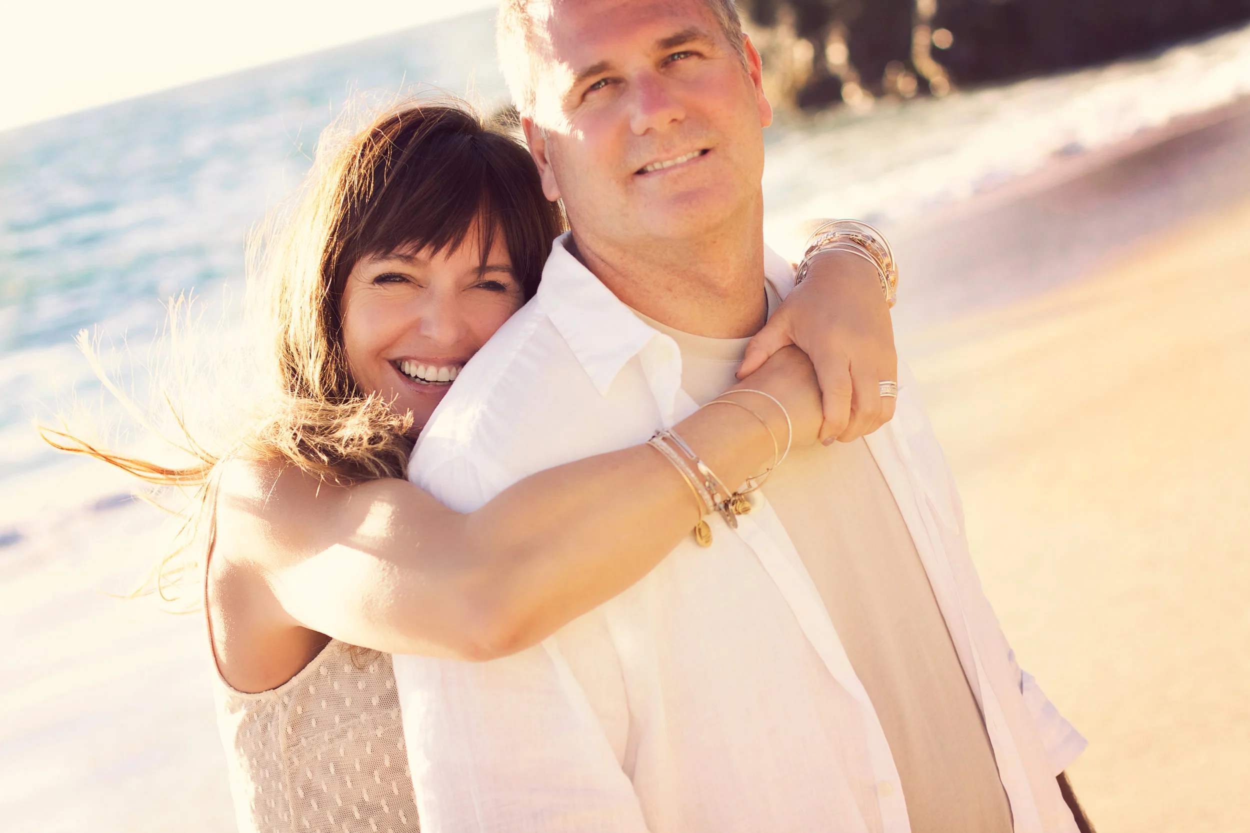 Happy couple posing at San Clemente Beach in Orange County for their engagement portraits. Natural and organic smiles as the wind blows.
