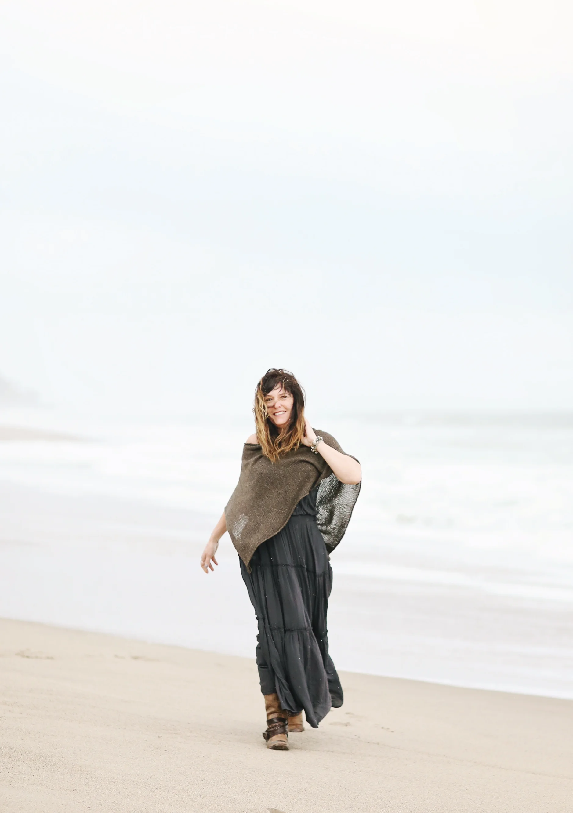Fine art image of woman walking on the beach in the breeze. Beach portrait.