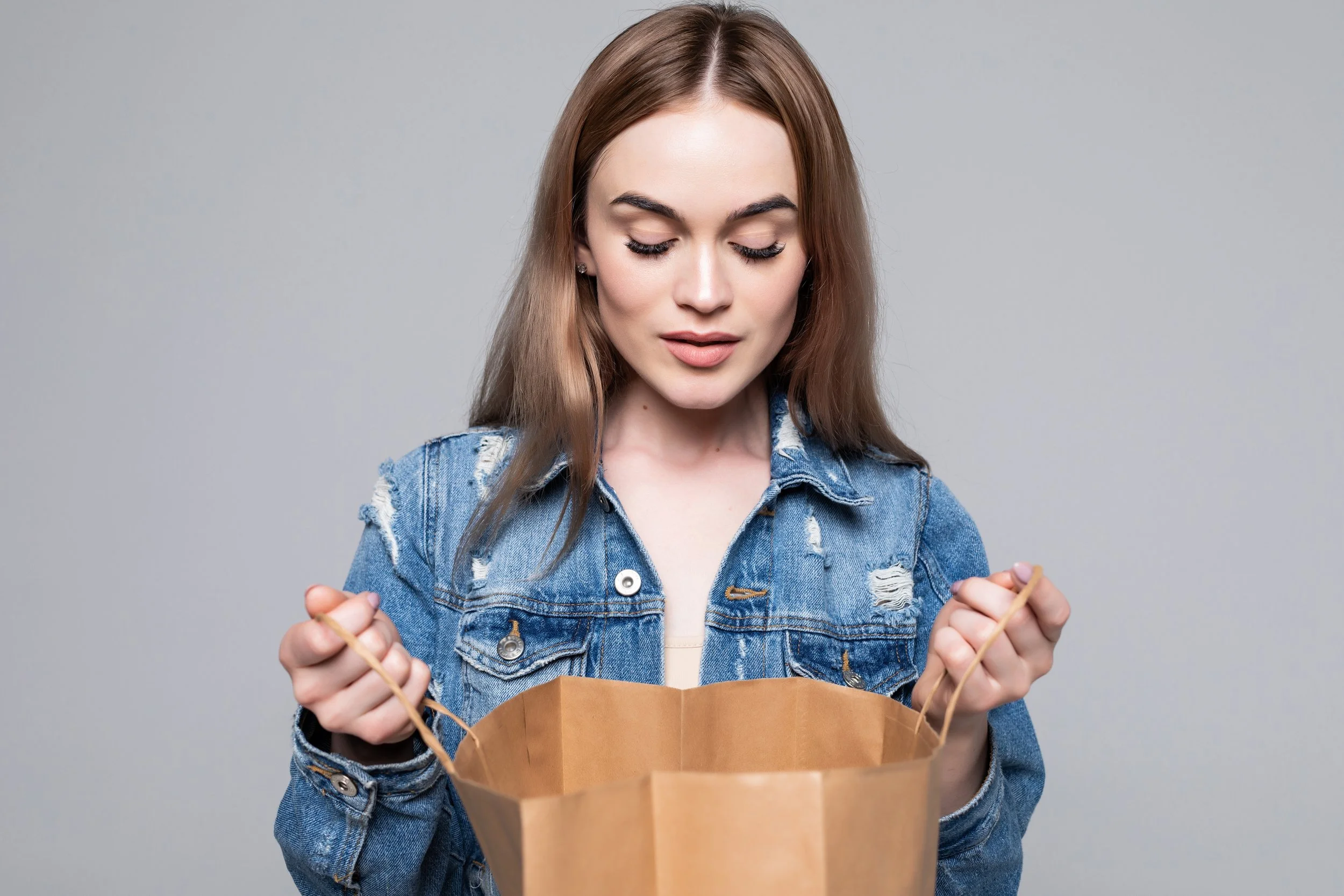 portrait-curious-young-woman-looking-inside-shopping-bags-gray-wall.jpg