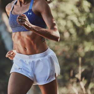  Woman running in white Under Armour running shorts and blue Under Armour sports bra 