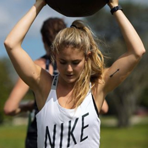  Alex Silver-Fagan Instagram model wearing white Nike tank top holding weight above head 