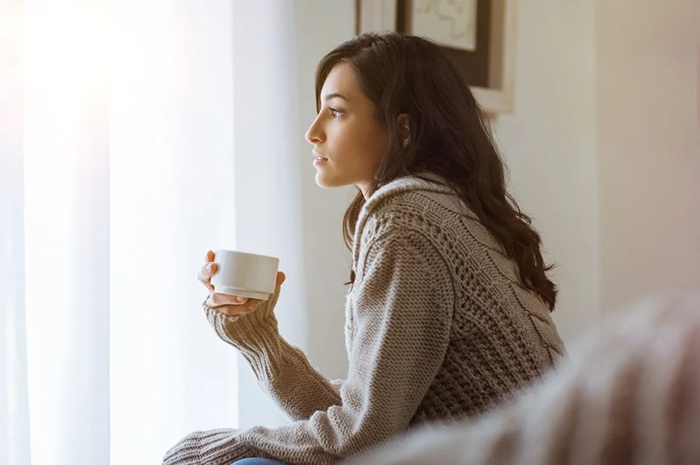 Woman-looking-out-the-window-with-drink.jpg
