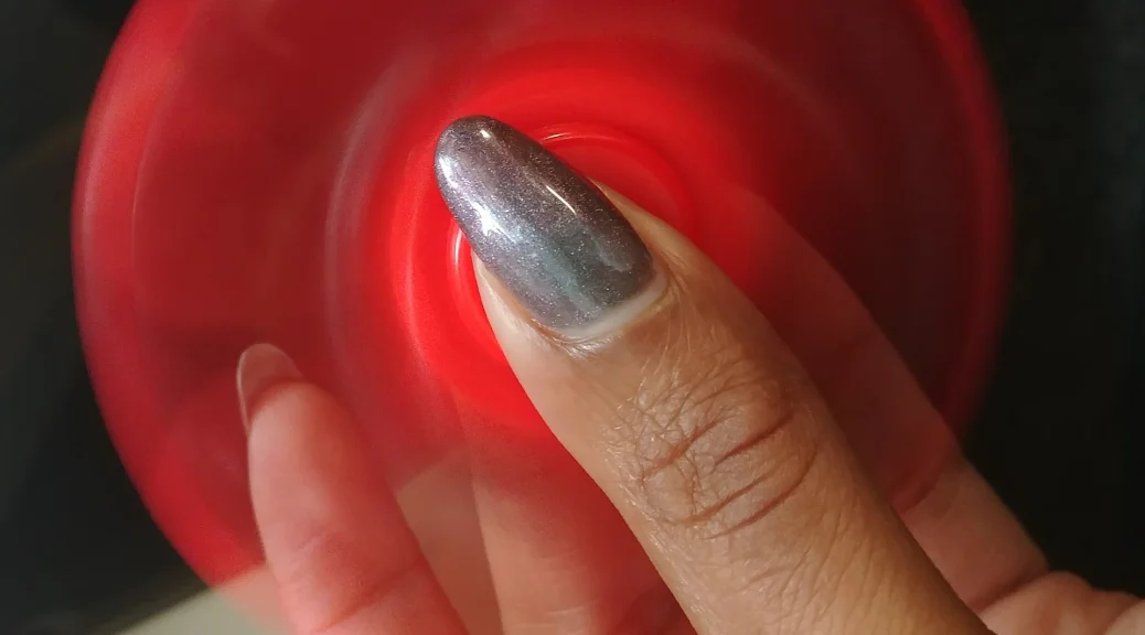 Photo Description: ChrisTiana ObeySumner’s hand holding a spinning fidget spinner