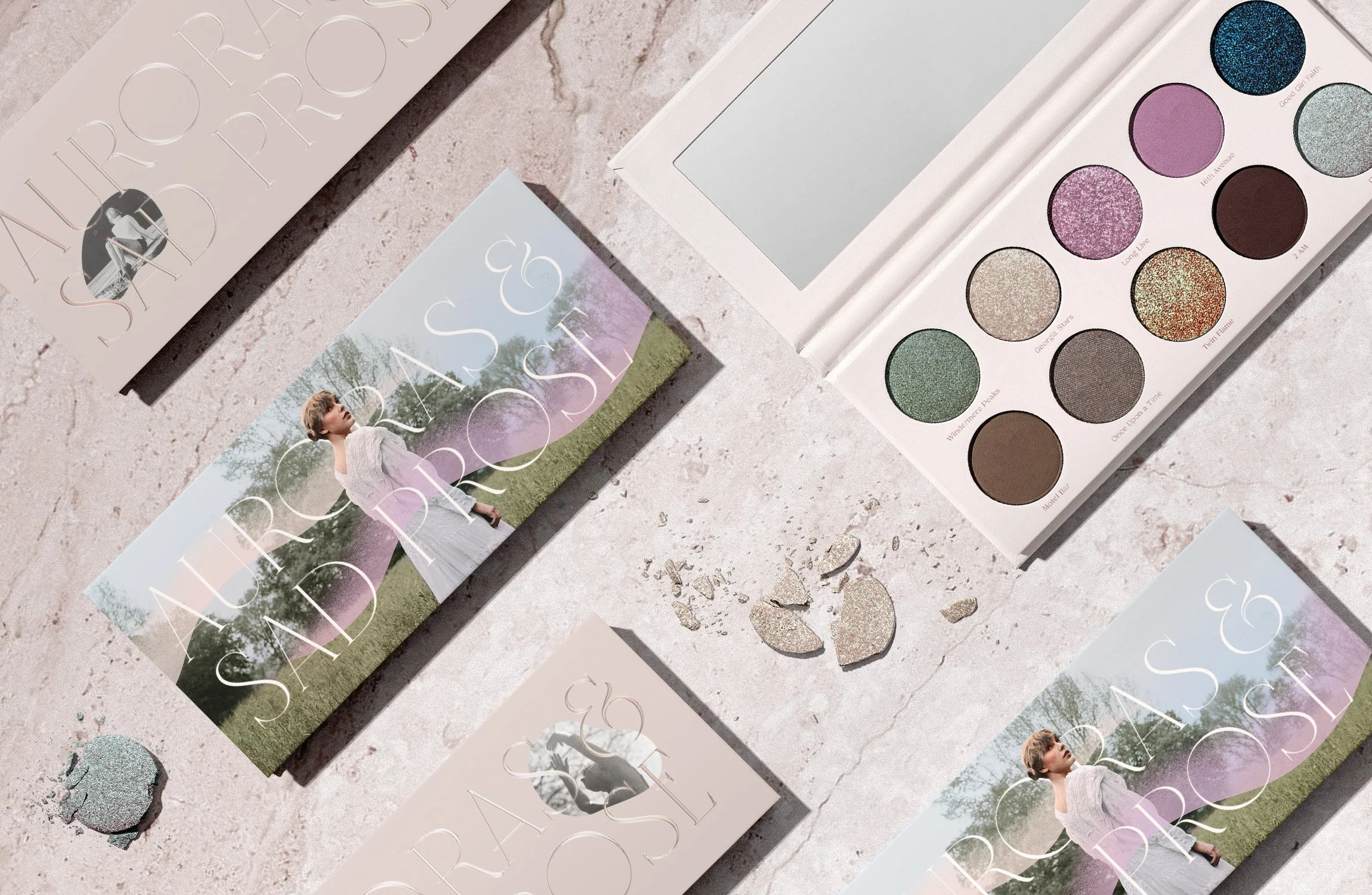 Open eyeshadow palette with twelve colorful shades and two promotional cards with woman in white dress on a pink textured surface.