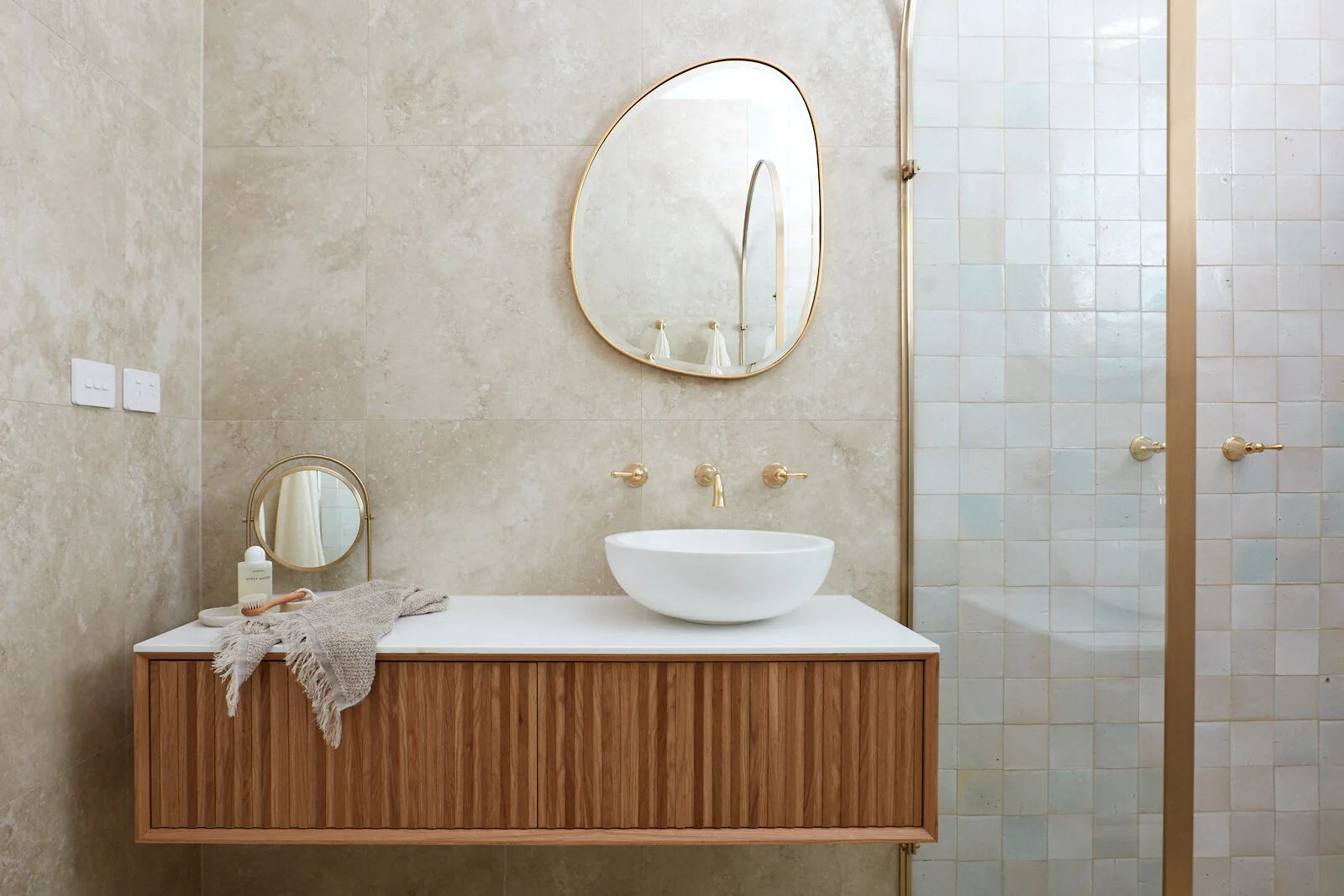 Three Birds Renovations House 13 bathroom vanity with fluted timber cabinetry, a vessel basin, brass tapware and natural stone finishes.